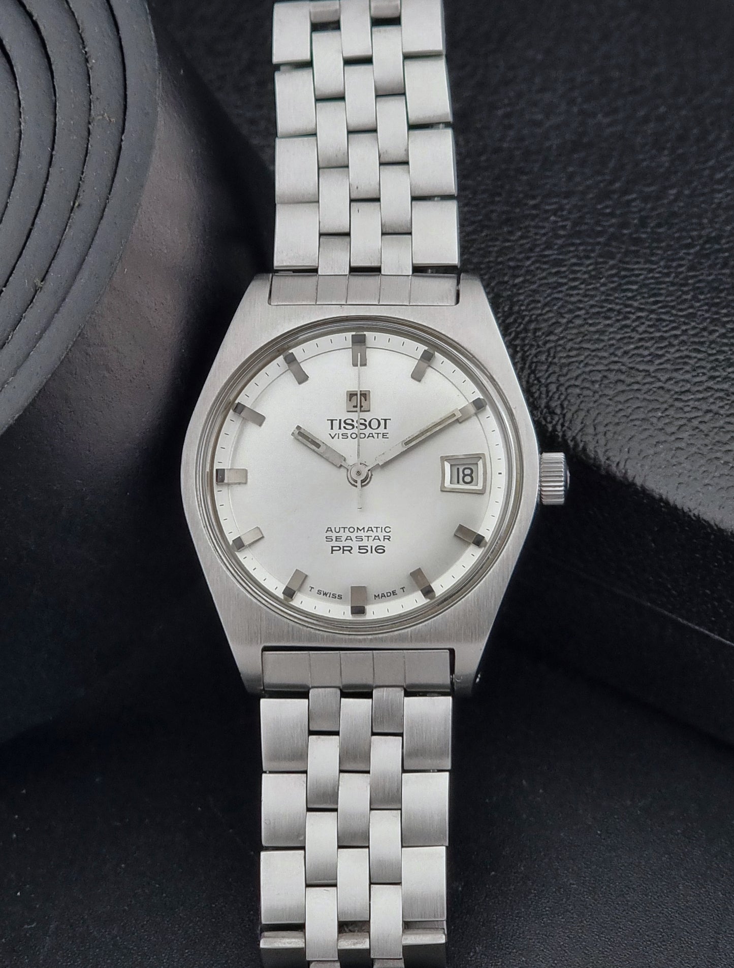 Tissot Seastar Visodate watch with a white face on a dark textured background