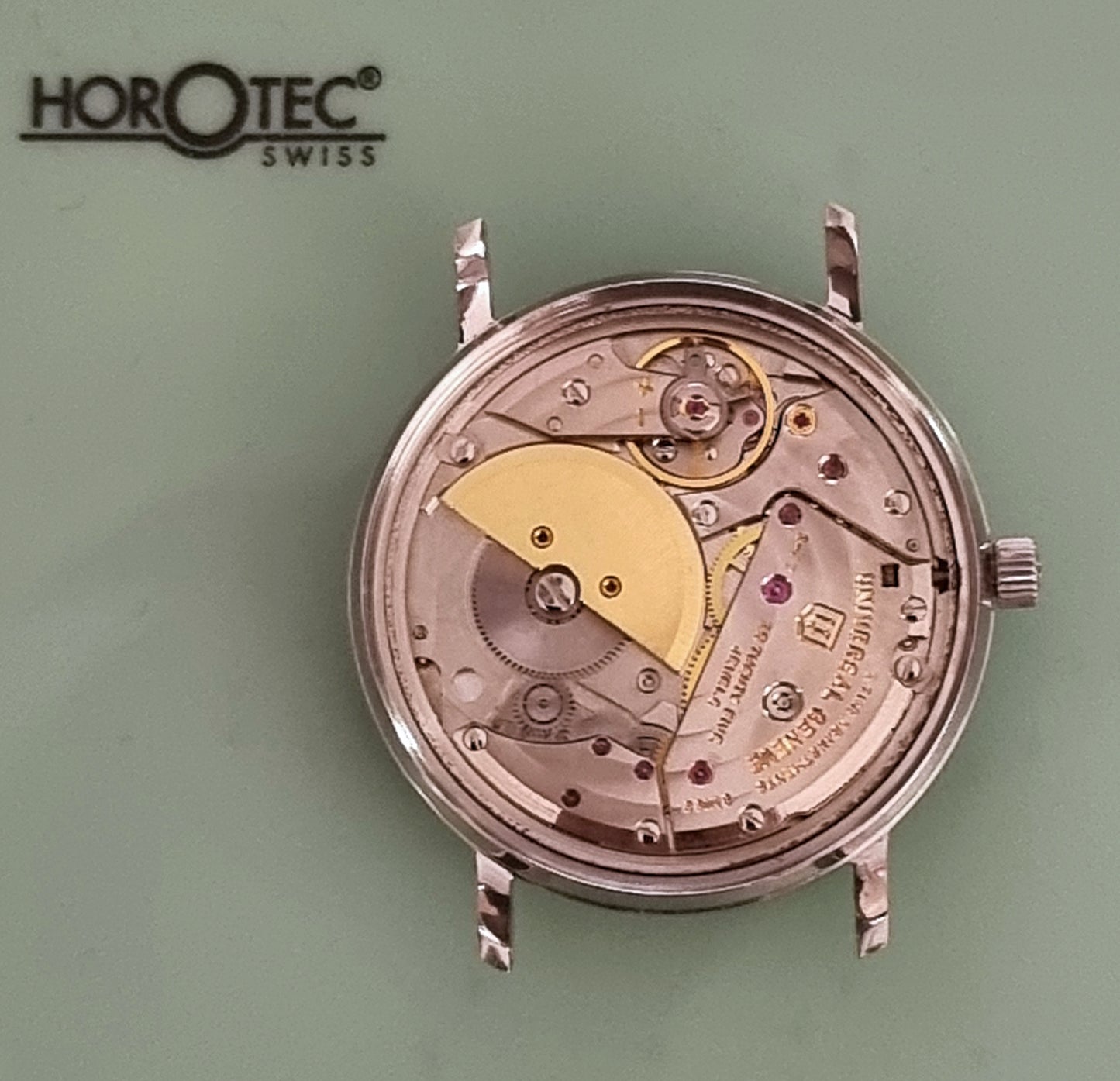 Universal Geneve Watch mechanism on a green background with Horotec Swiss branding.