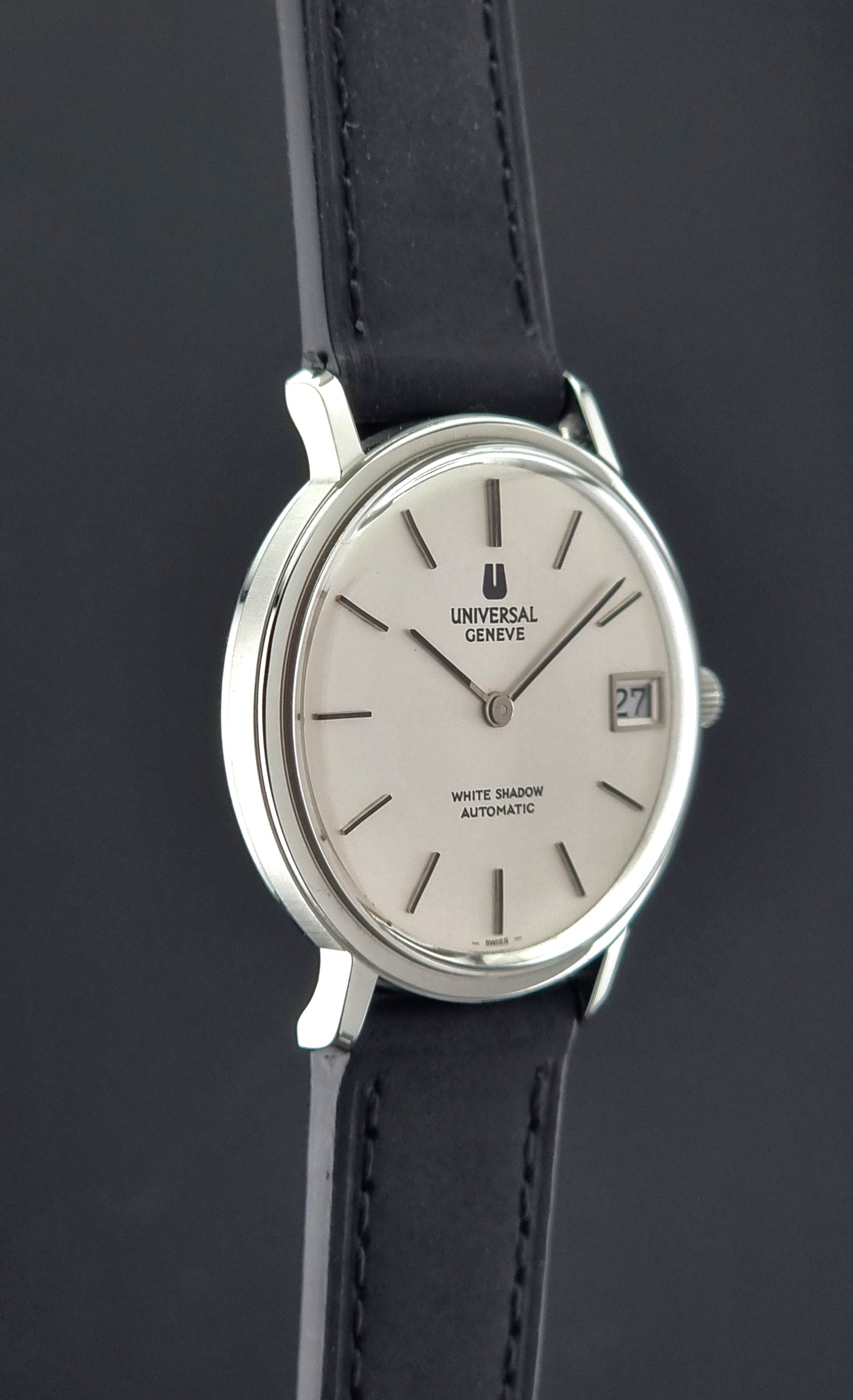Wristwatch Universal Geneve with black leather strap and silver case on a dark background