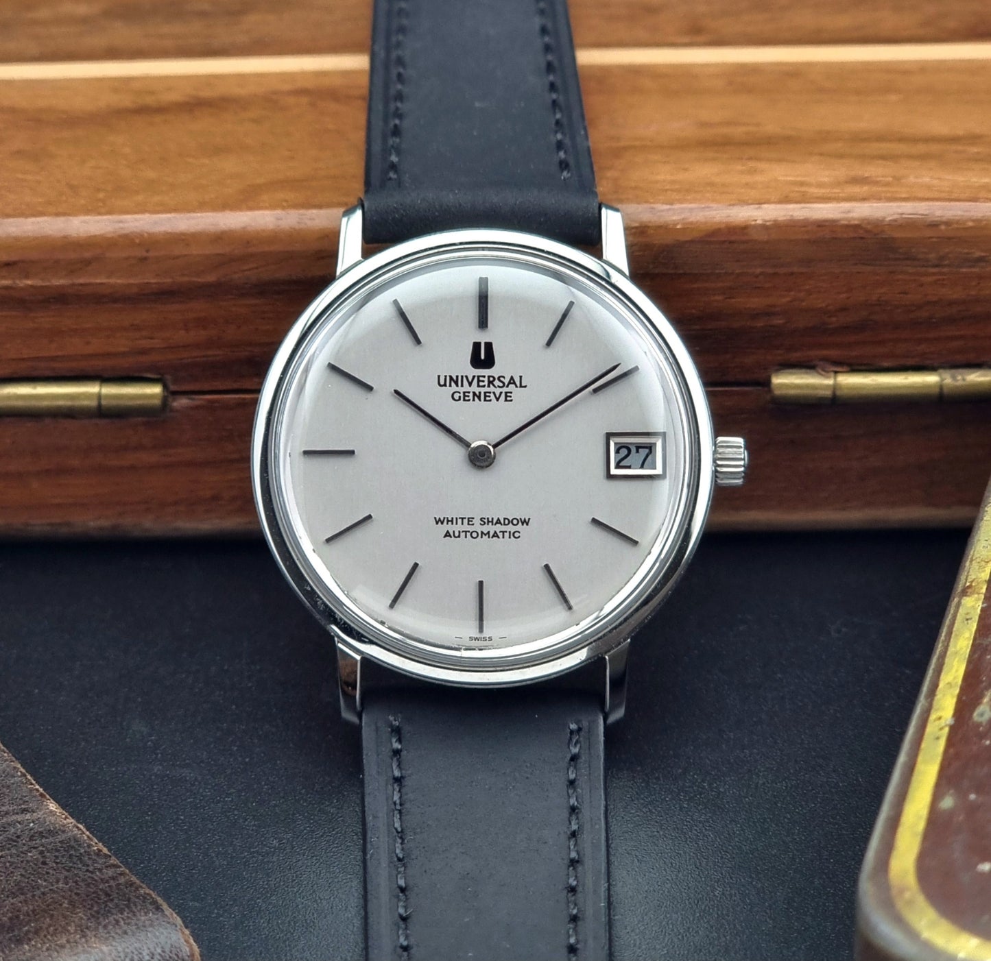 Universal Geneve Watch with black strap and silver case on a wooden surface