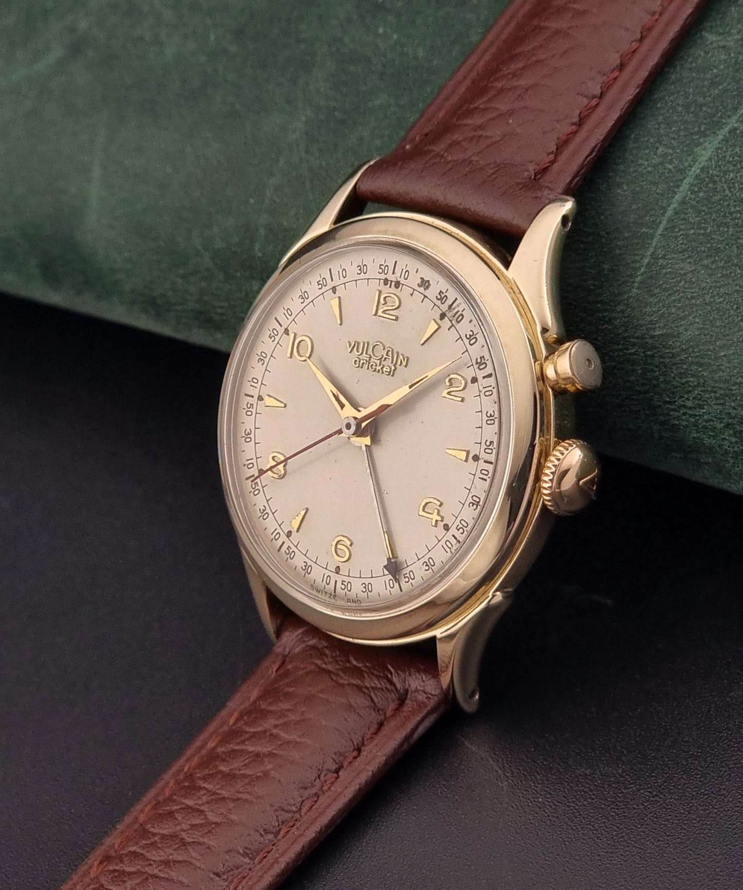 Vulcain cricket W197446 Watch with brown leather strap and gold casing on a dark surface