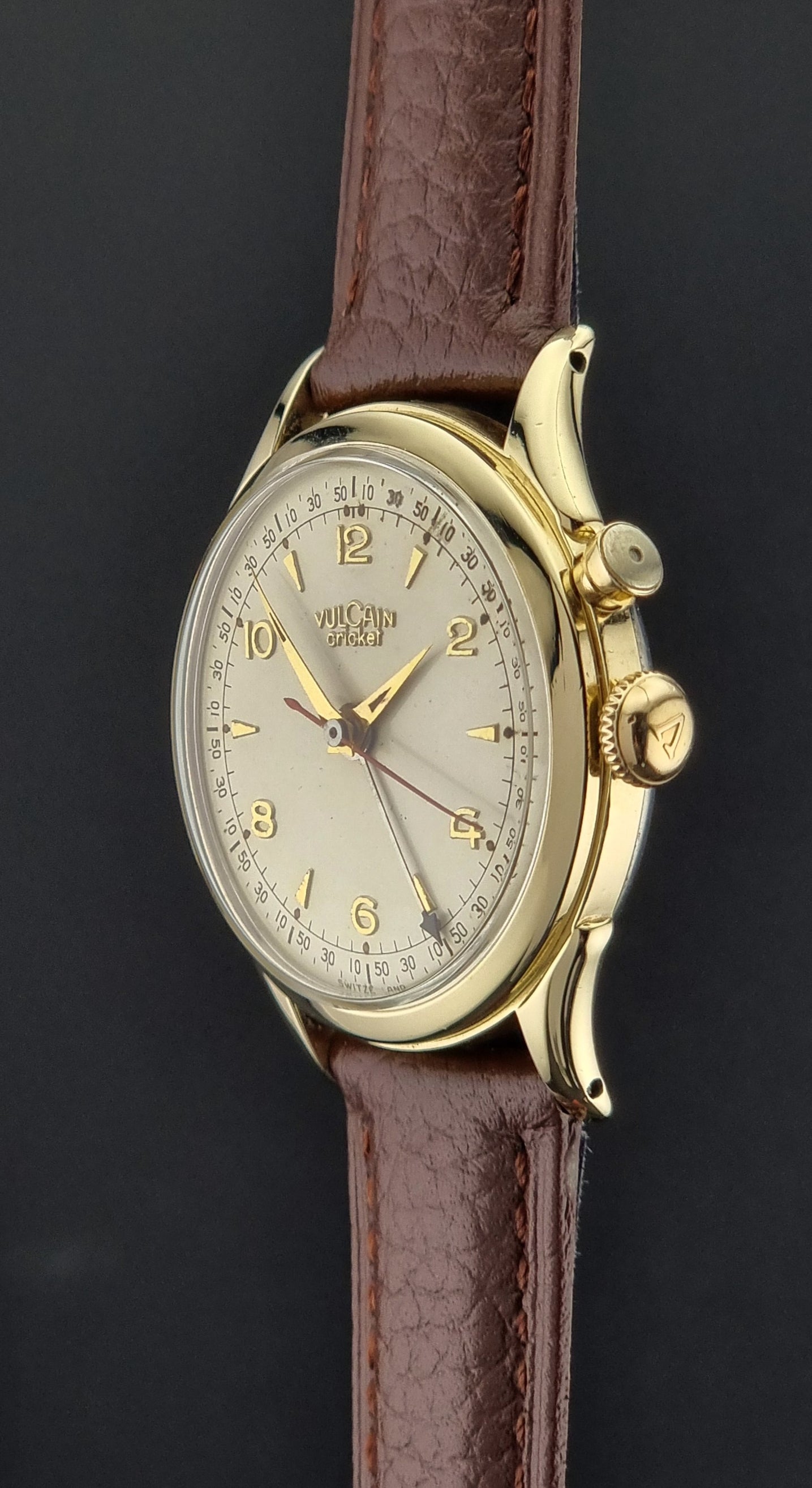 Vintage Vulcain cricket W197446 watch with brown leather strap and gold casing on a dark background