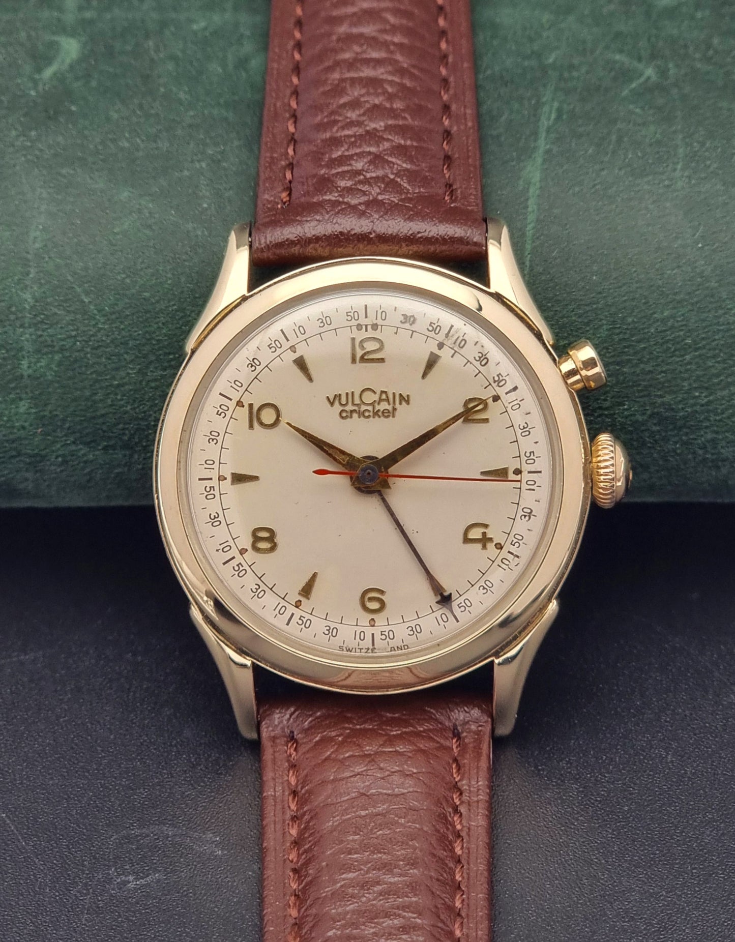 Vintage Vulcain cricket W197446 watch with brown leather strap on a green and black textured background