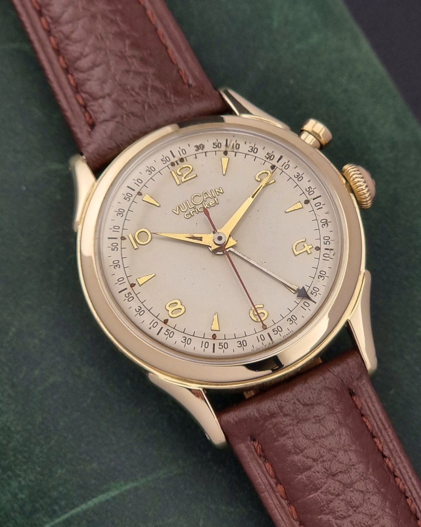 Vintage Vulcain cricket W197446 watch with brown leather strap and gold casing on a green textured background