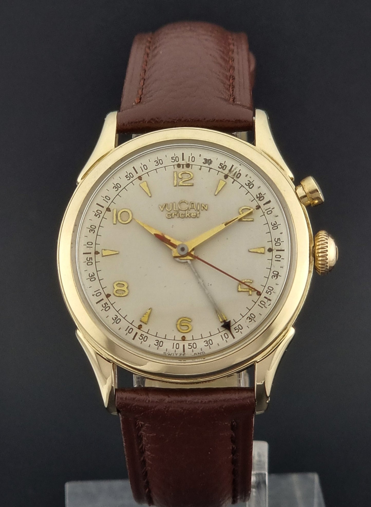 Vintage Vulcain cricket W197446 wristwatch with gold case and brown leather strap on a dark background