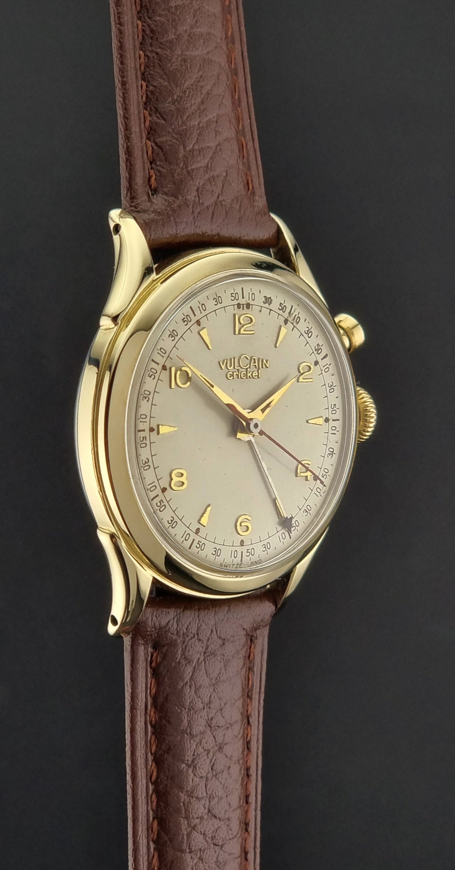 Vintage Vulcain cricket W197446 watch with gold case and brown leather strap on a dark background