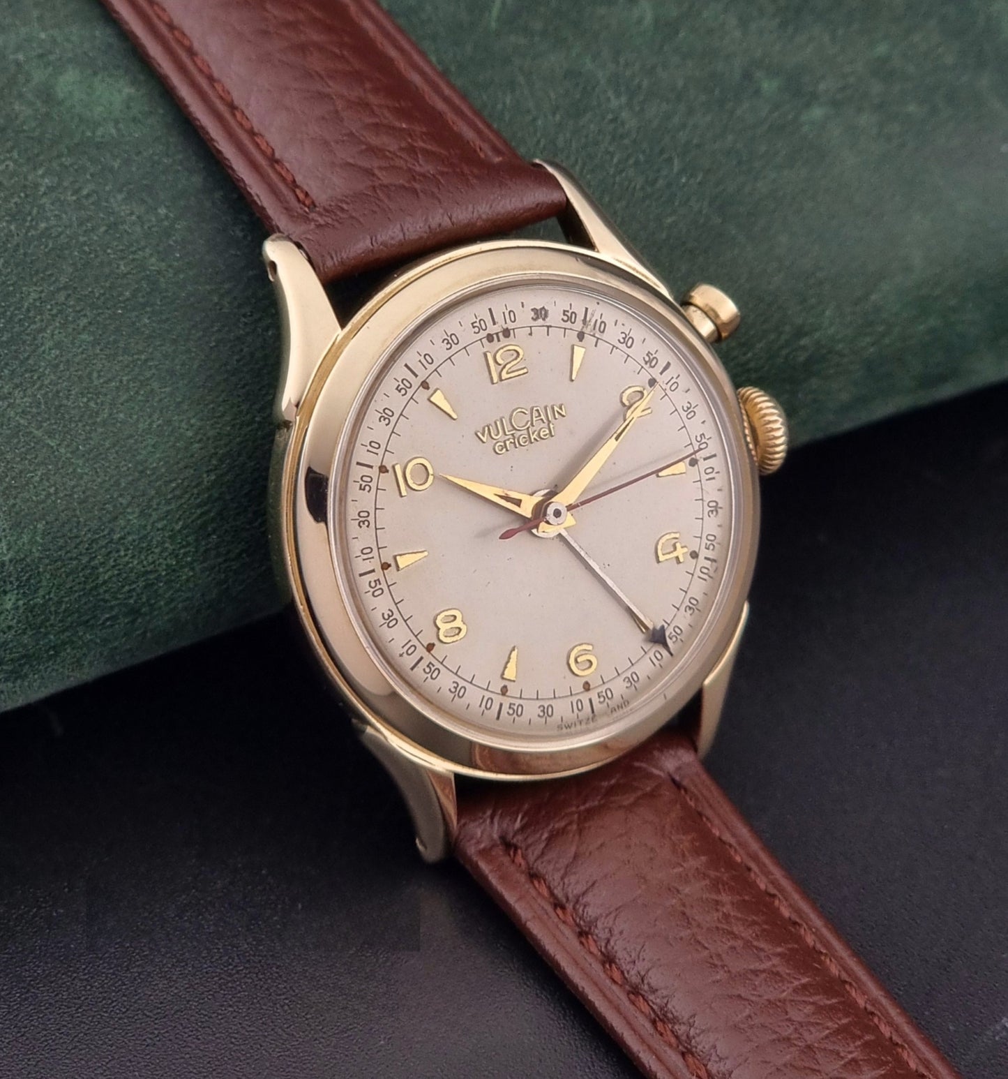 Vulcain cricket W197446 Watch with brown leather strap and gold case on a dark green background