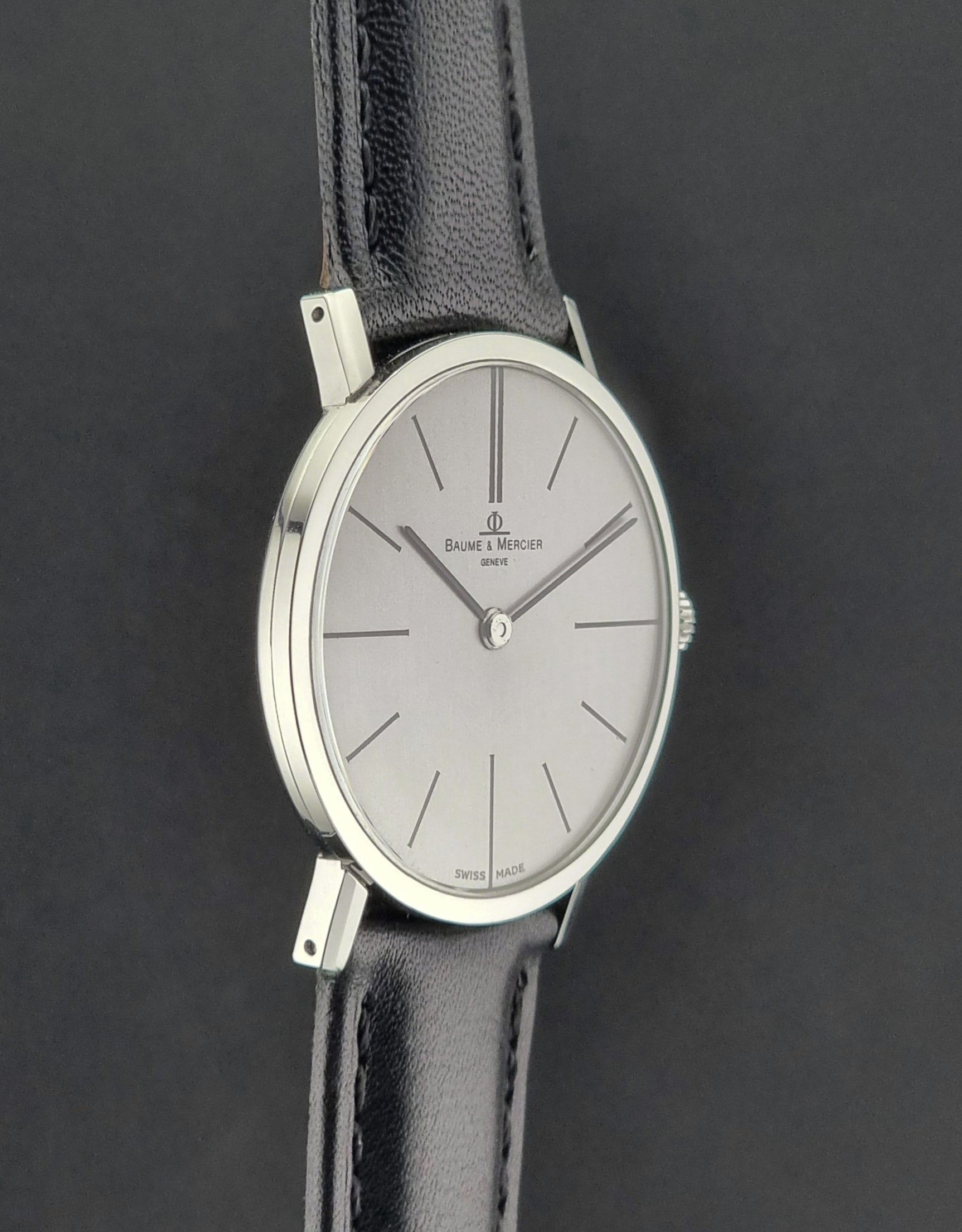 Baume et Mercier Wristwatch with black leather strap and silver case on a dark background