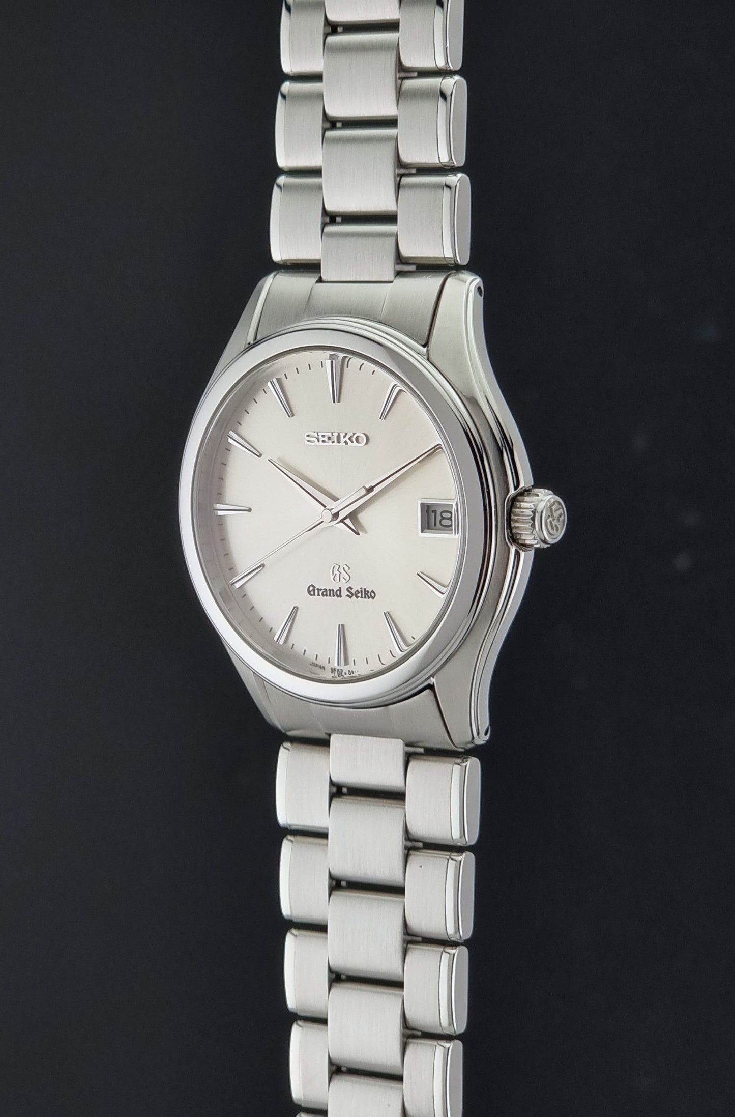 A Grand Seiko SBGX005 quartz watch 9F62-0A10 Sunburst Dial  with bracelet on a dark back ground a crown side profile view