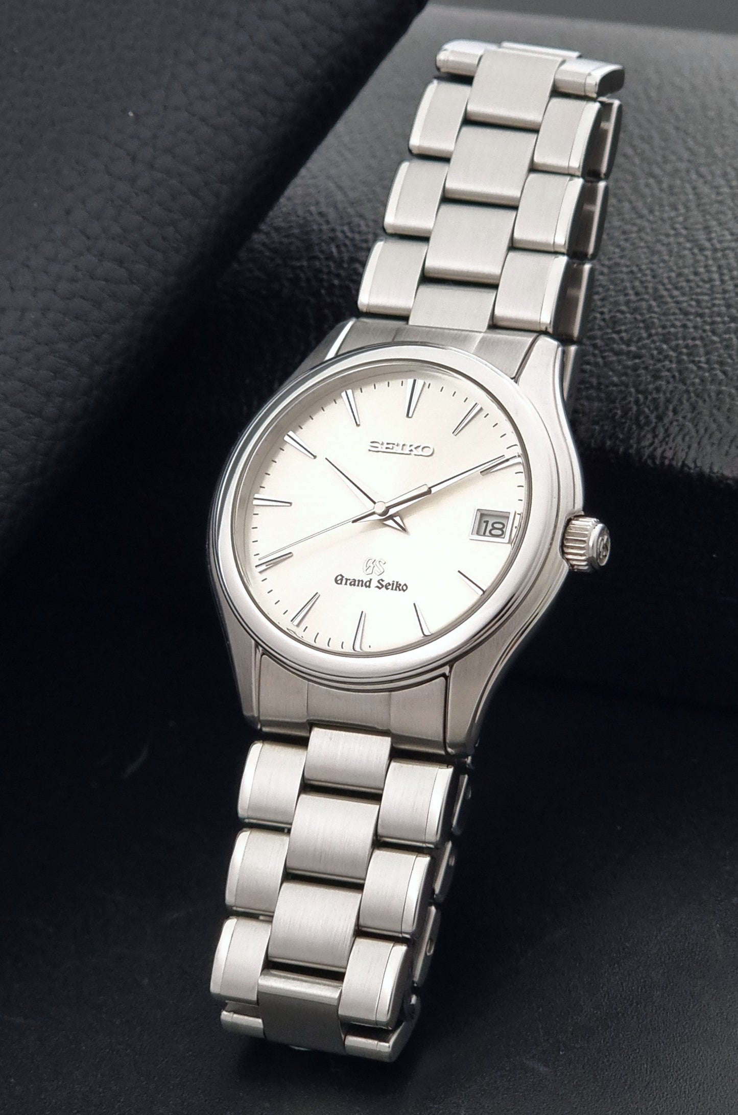 A Grand Seiko SBGX005 quartz watch 9F62-0A10 Sunburst Dial  with bracelet on a dark back ground resting on a textured background