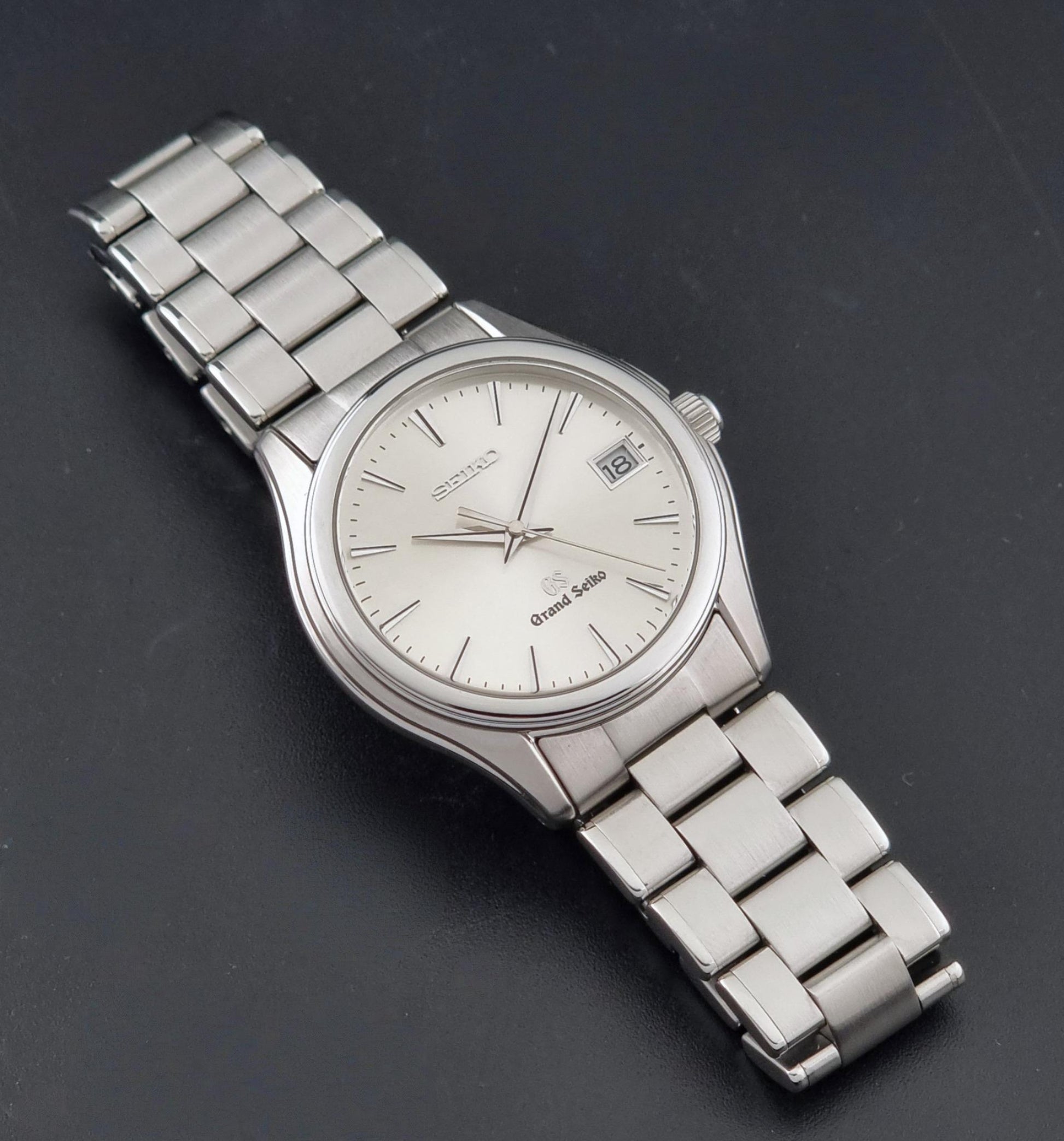A Grand Seiko SBGX005 quartz watch 9F62-0A10 Sunburst Dial  with bracelet on a dark back ground a front view