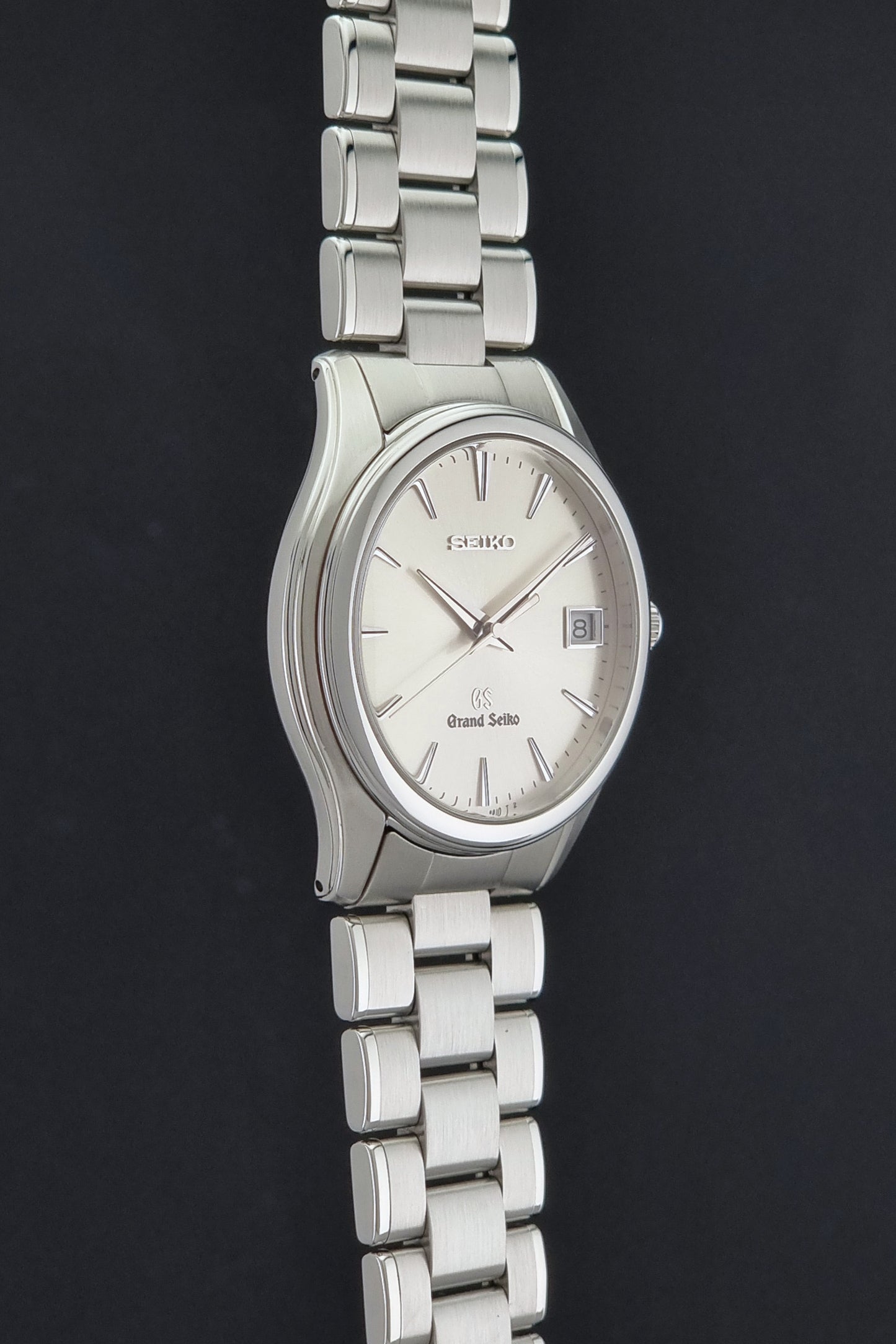 A Grand Seiko SBGX005 quartz watch 9F62-0A10 Sunburst Dial  with bracelet on a dark back ground a side profile view