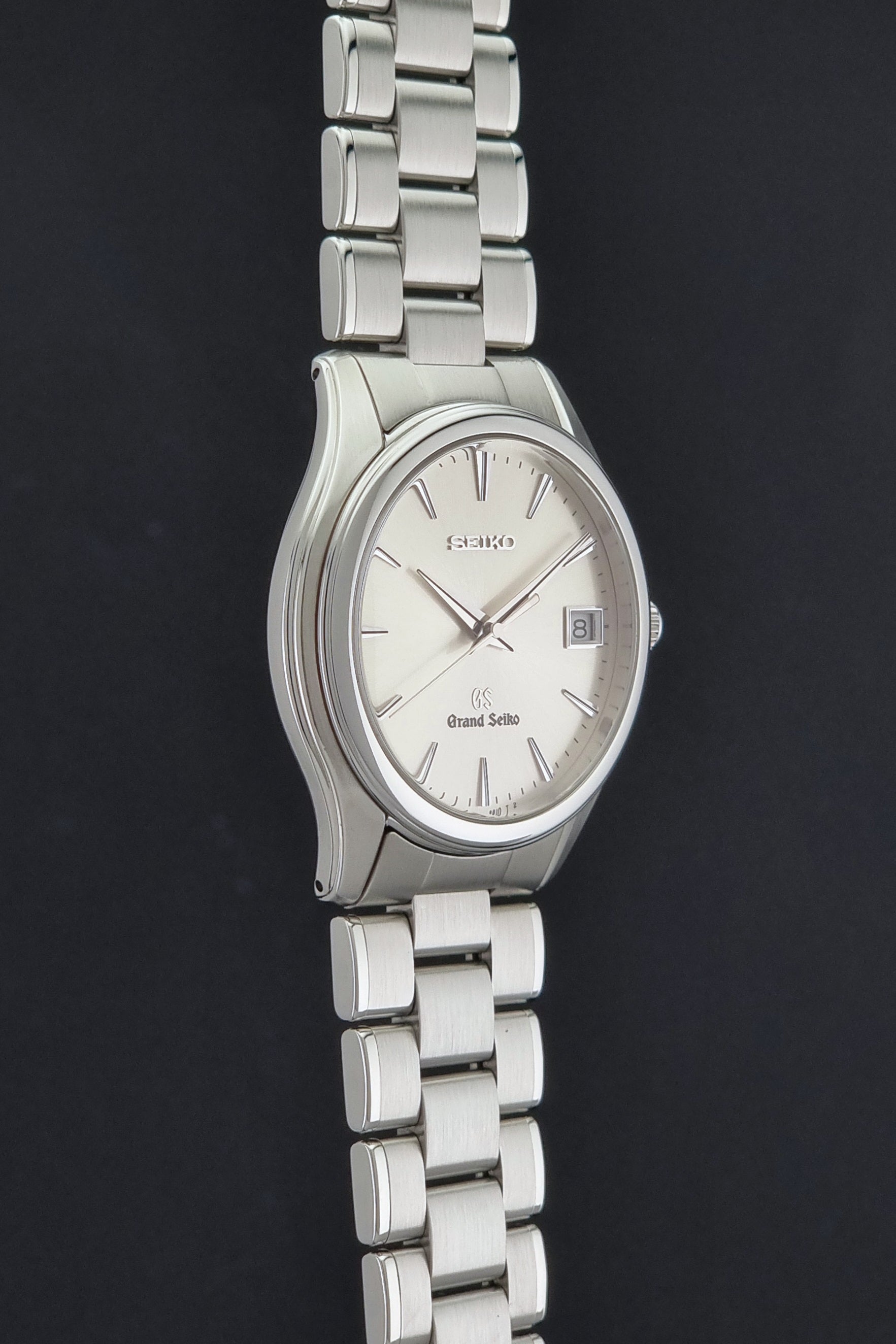 A Grand Seiko SBGX005 quartz watch 9F62-0A10 Sunburst Dial  with bracelet on a dark back ground a side profile view