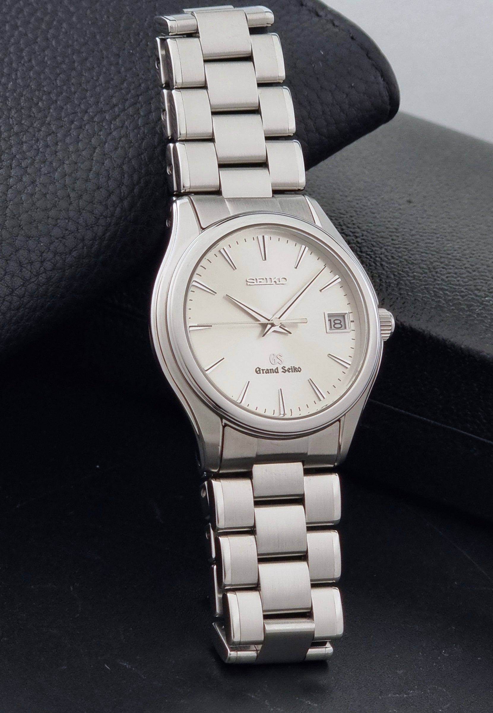 A Grand Seiko SBGX005 quartz watch 9F62-0A10 Sunburst Dial  with bracelet on a dark back ground resting n a textured background