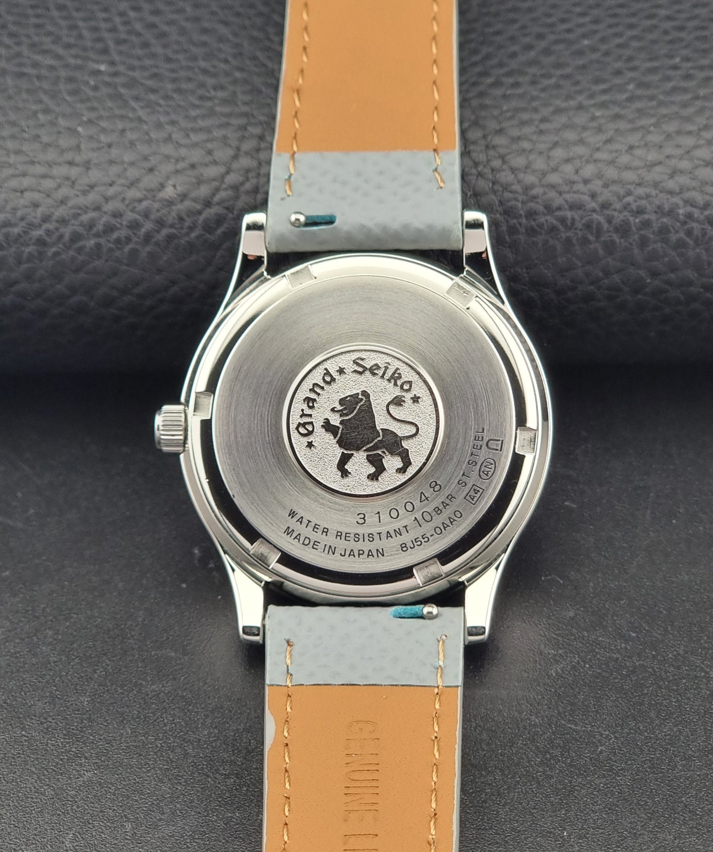 Grand Seiko SBGF029 quartz watch 8J55-0AA0  with light grey strap and silver case on a dark grey background case back view