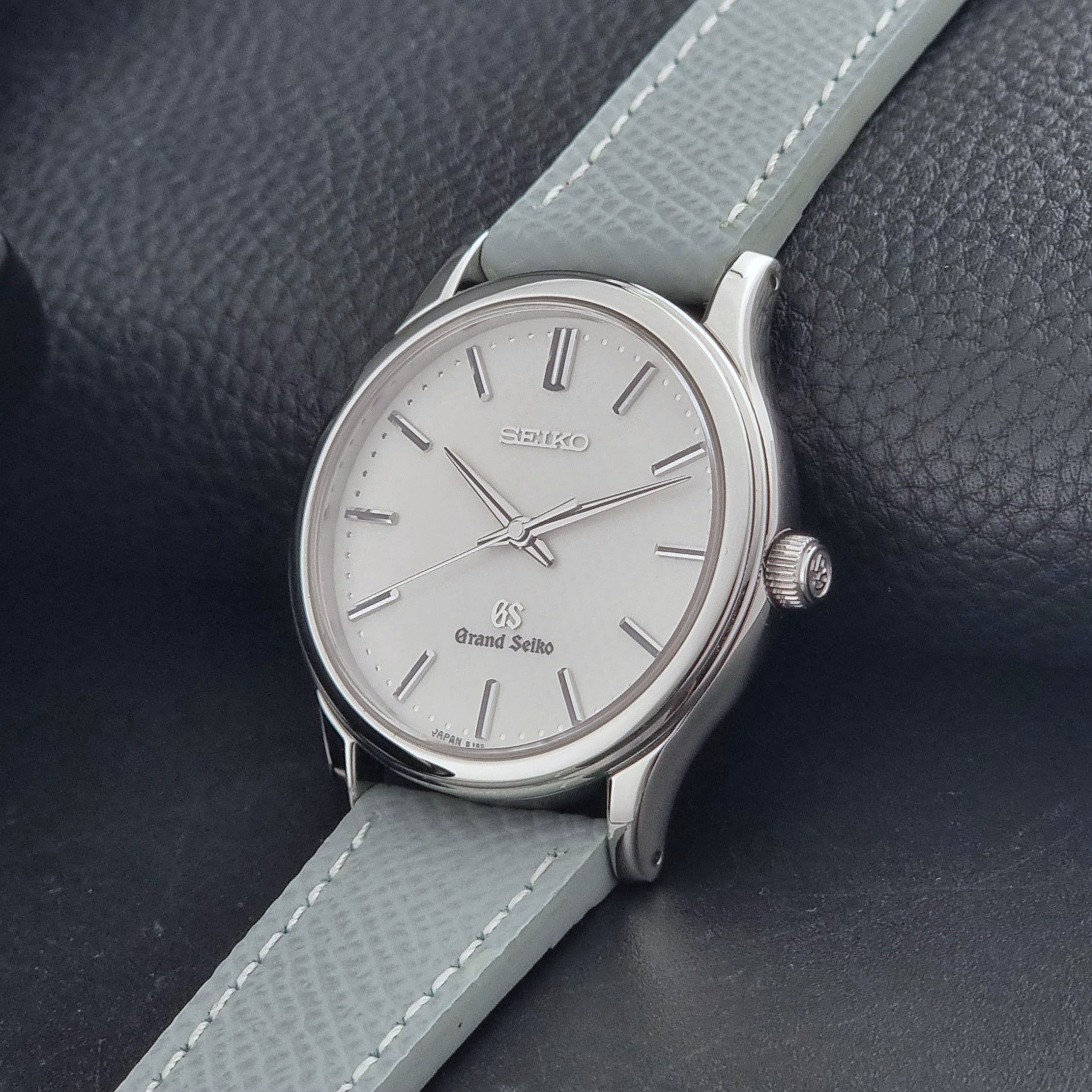 Grand Seiko SBGF029 quartz watch 8J55-0AA0  with light grey strap and silver case on a dark grey background crown view
