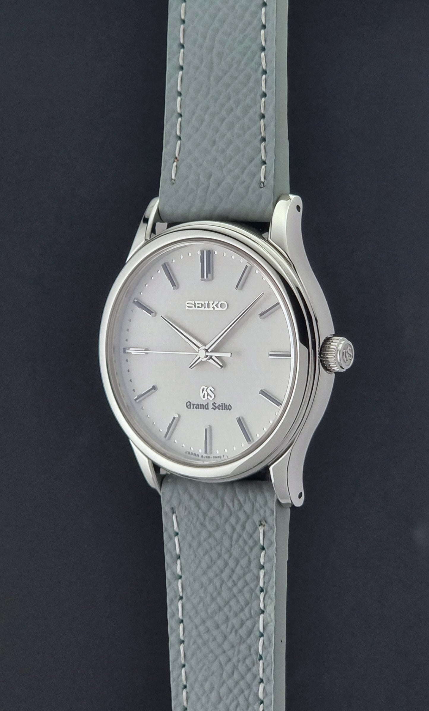 Grand Seiko SBGF029 quartz watch 8J55-0AA0  with light grey strap and silver case on a dark grey background crown profile view