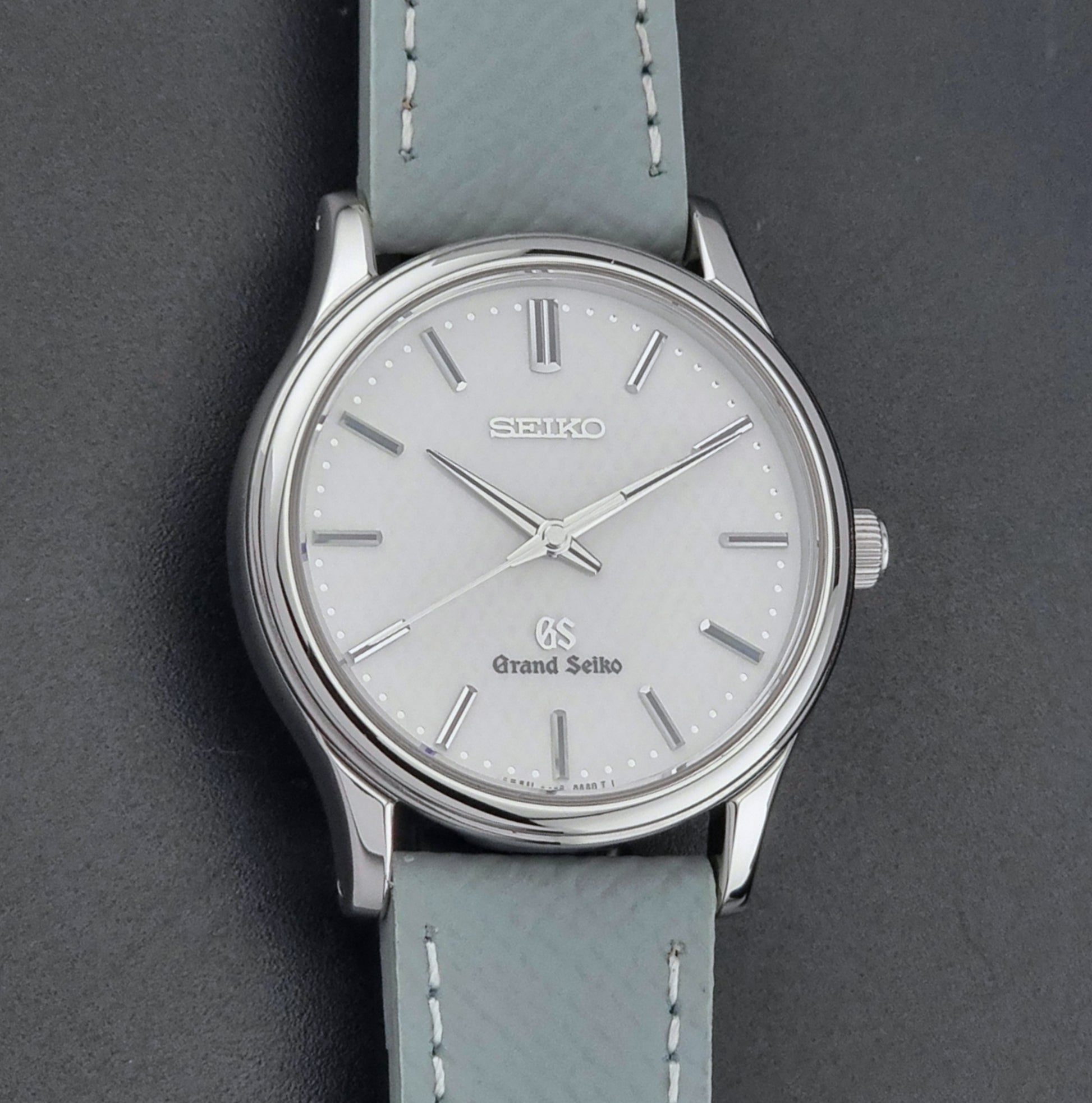 Grand Seiko SBGF029 quartz watch 8J55-0AA0  with light grey strap and silver case on a dark grey background front view