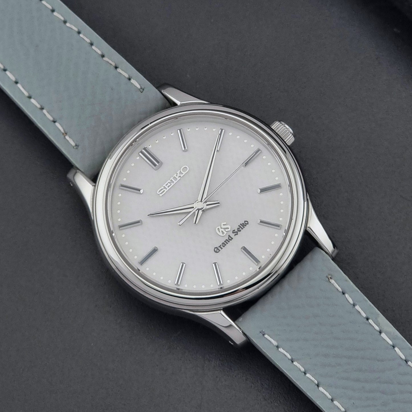 Grand Seiko SBGF029 quartz watch 8J55-0AA0  with light grey strap and silver case on a dark grey background close up dial view