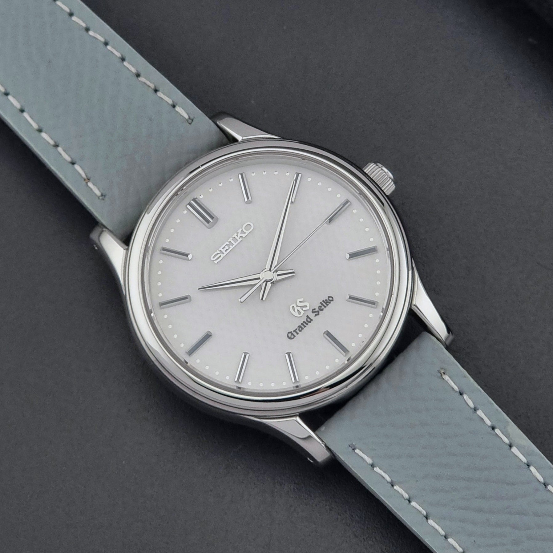Grand Seiko SBGF029 quartz watch 8J55-0AA0  with light grey strap and silver case on a dark grey background close up dial view