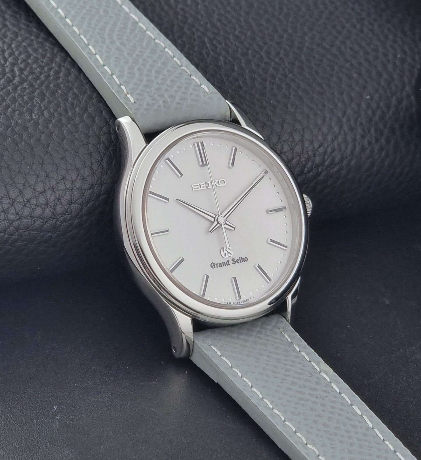 Grand Seiko SBGF029 quartz watch 8J55-0AA0  with light grey strap and silver case on a dark grey background side view