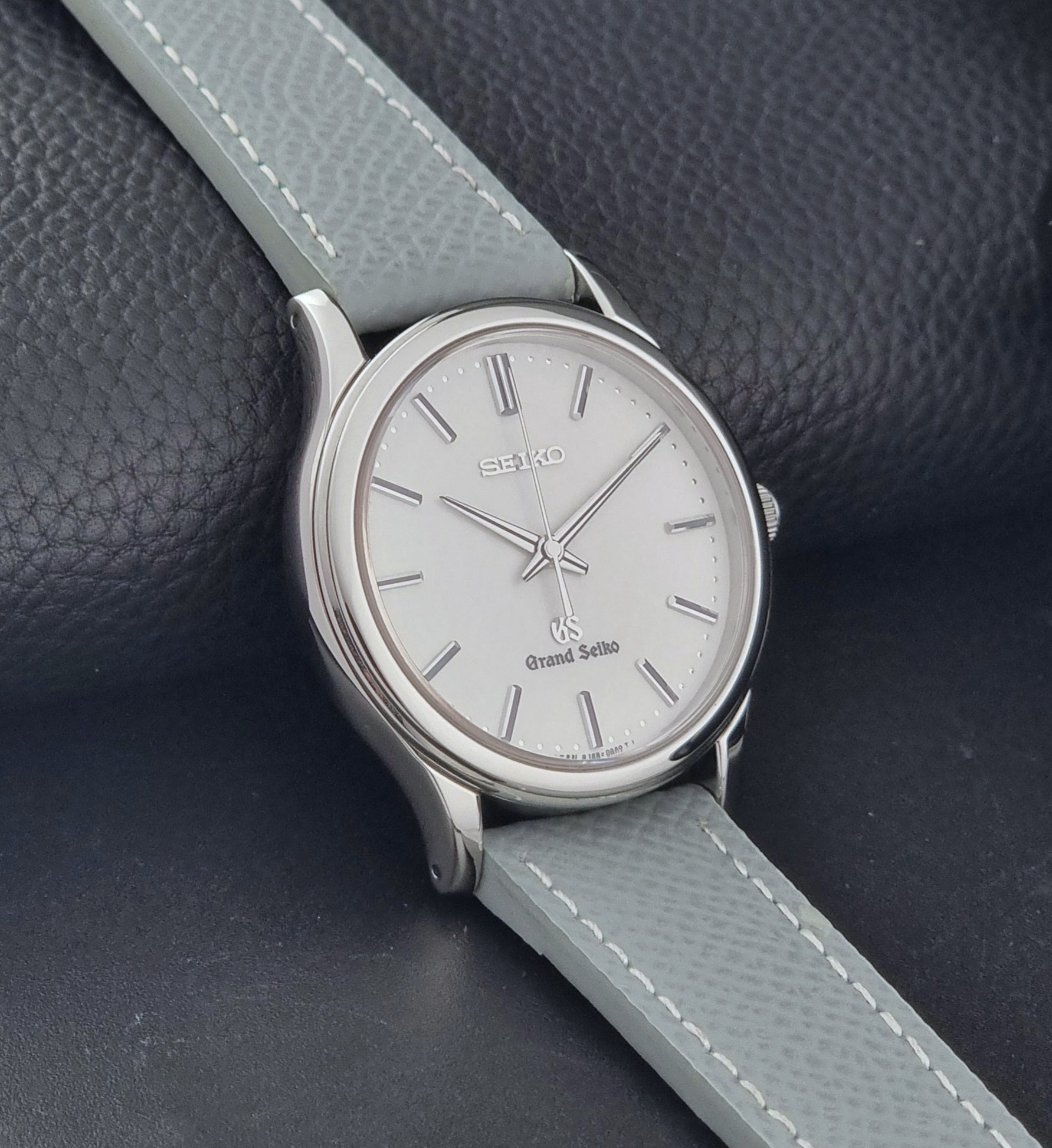 Grand Seiko SBGF029 quartz watch 8J55-0AA0  with light grey strap and silver case on a dark grey background side view