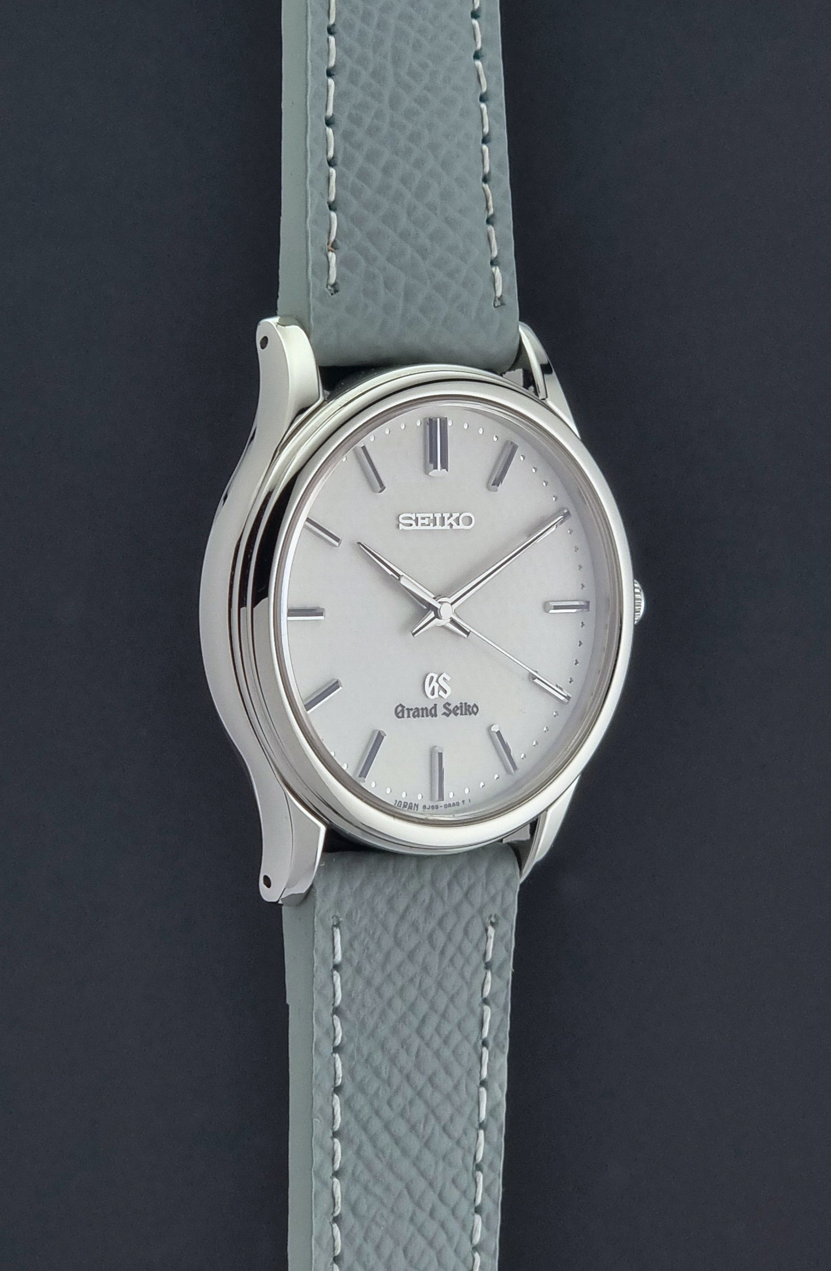 Grand Seiko SBGF029 quartz watch 8J55-0AA0  with light grey strap and silver case on a dark grey background side profile view