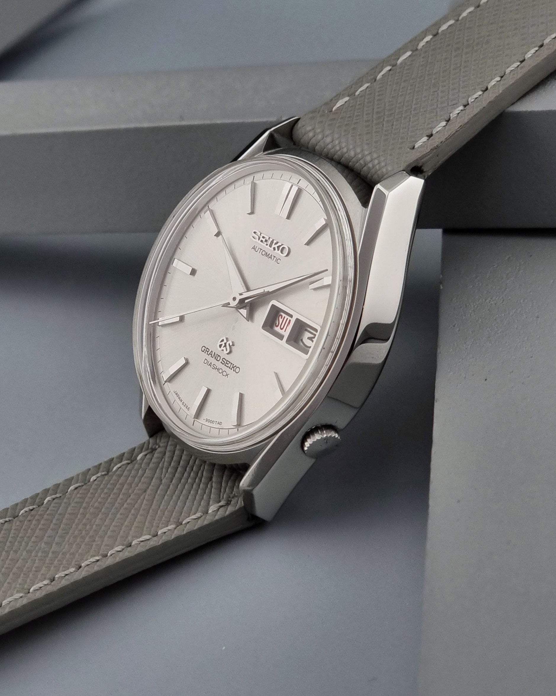 Vintage Grand Seiko watch with a gray strap on a gray surface