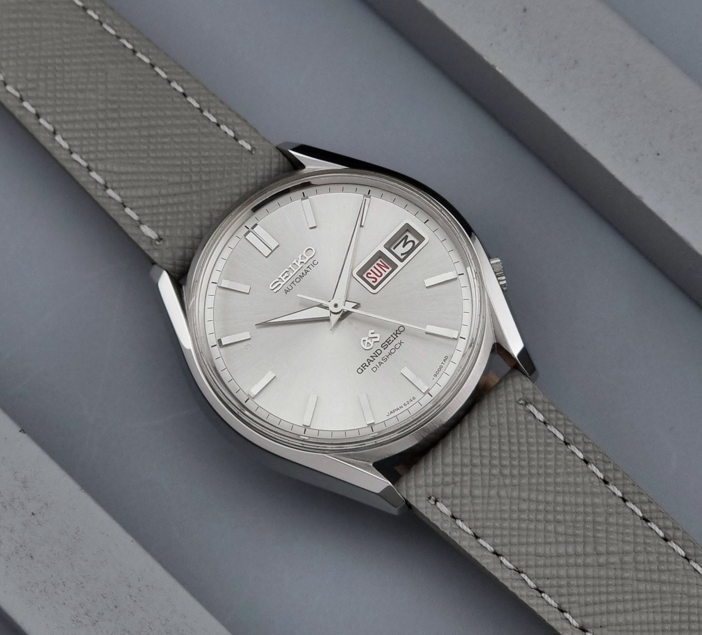 Vintage Grand Seiko watch with a textured strap on a gray background