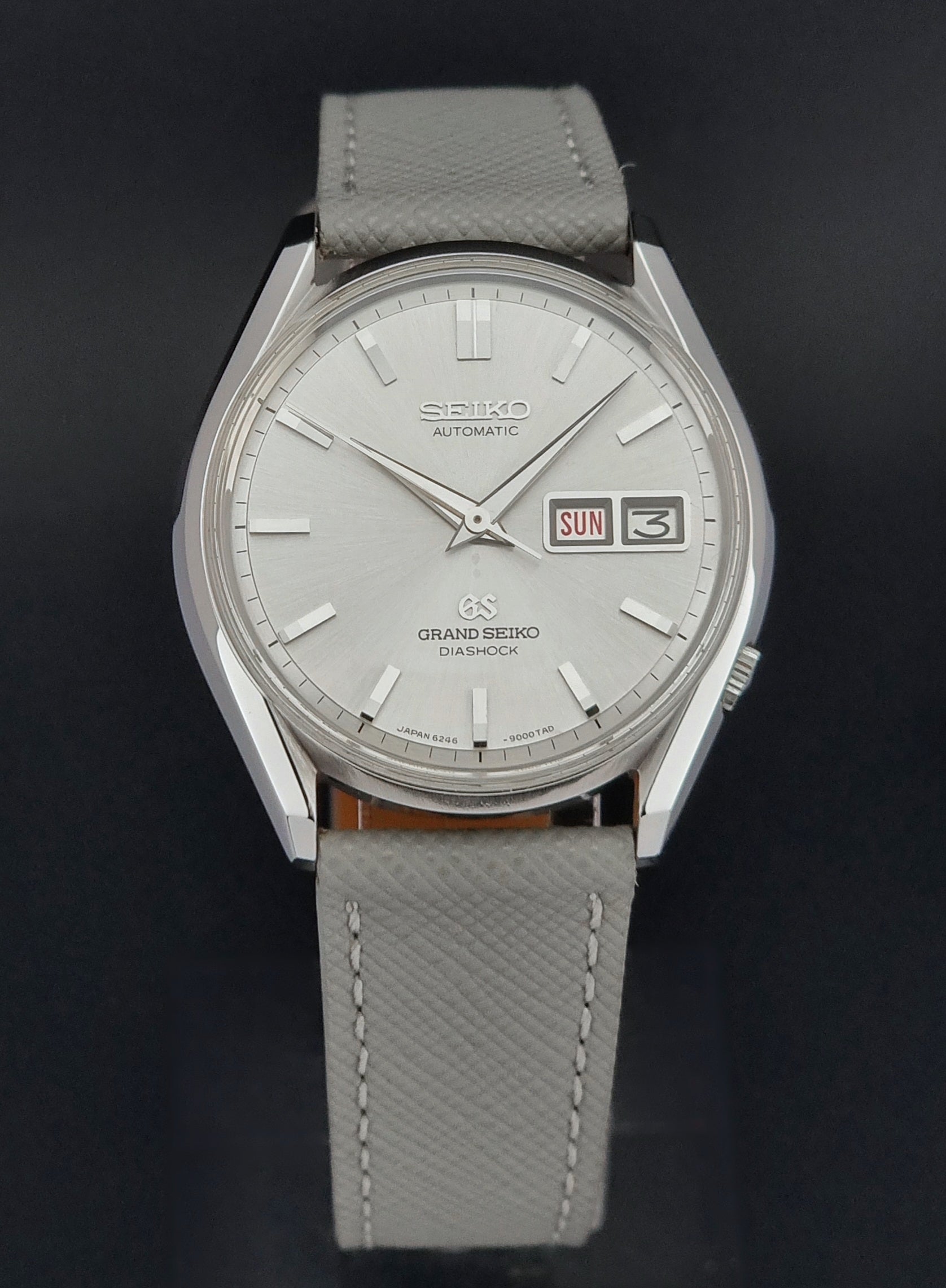 Vintage Grand Seiko watch with gray leather strap on a black background