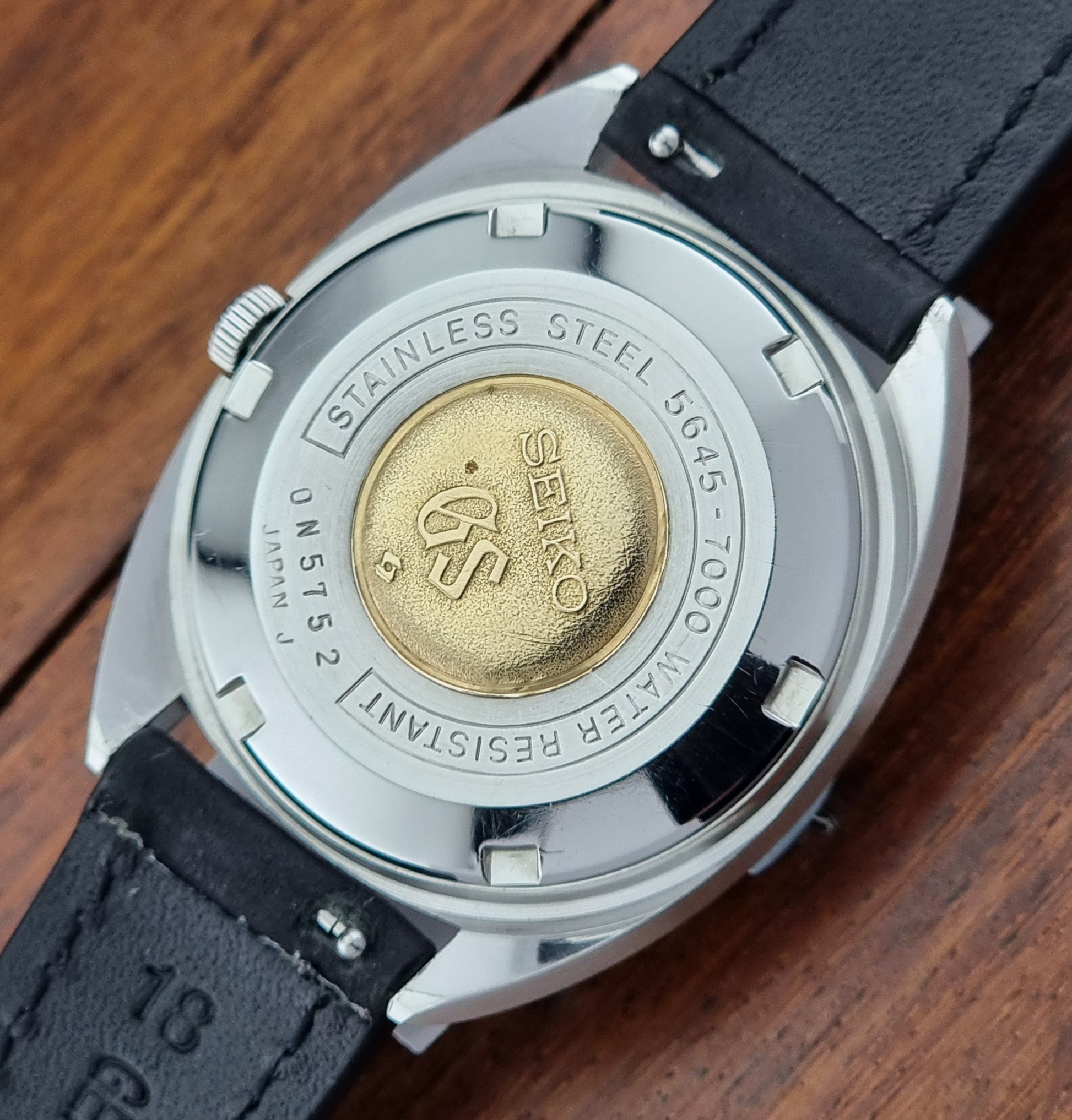 Grand Seiko Watch case with brand logo on a wooden surface