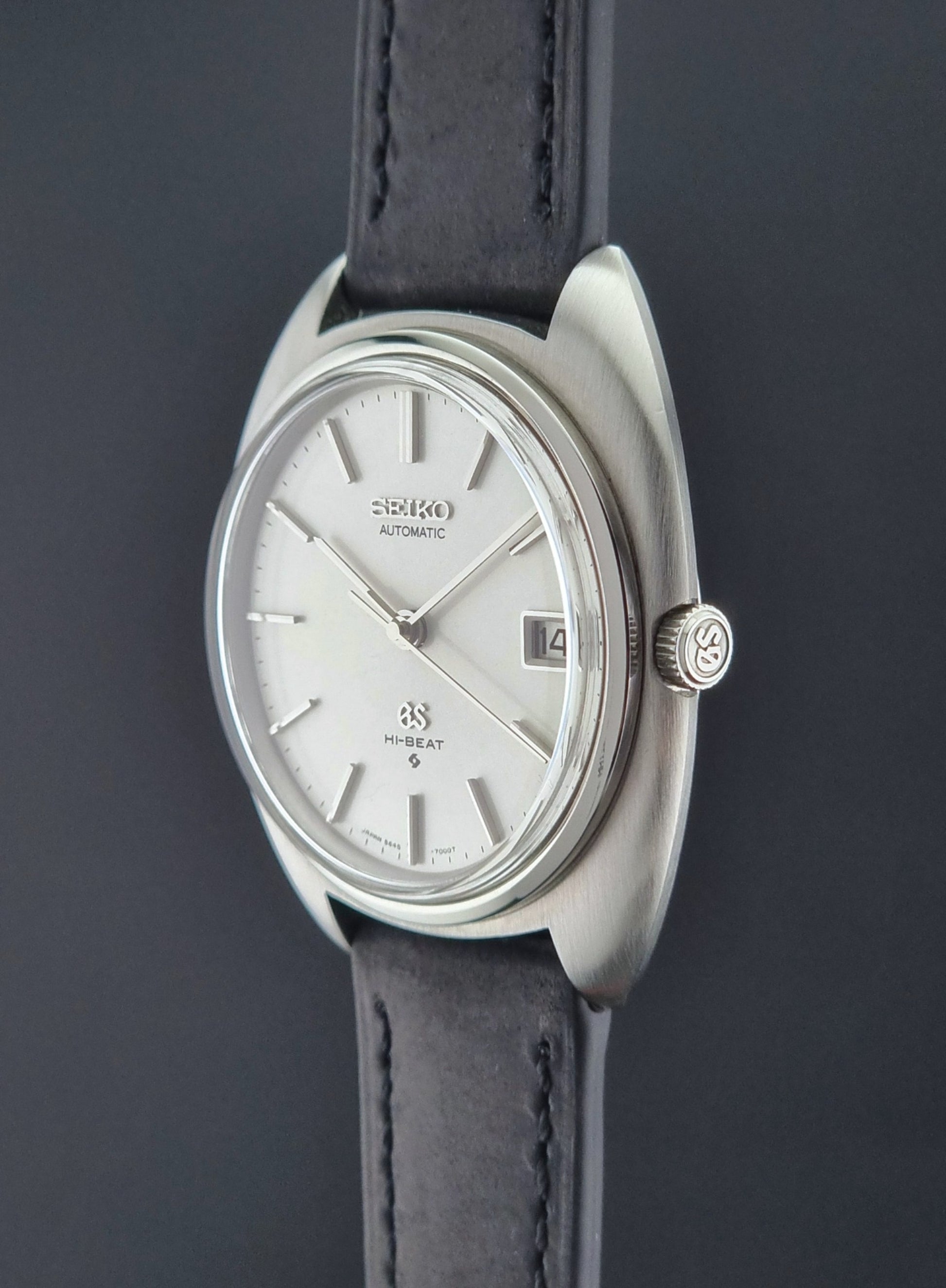 Grand Seiko watch with silver dial and black leather strap on a dark background