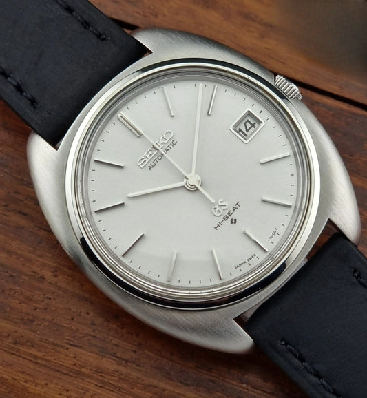 Grand Seiko watch with black leather strap on a wooden surface