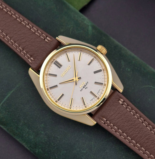 Vintage King Seiko watch with gold case and brown leather strap on a green surface