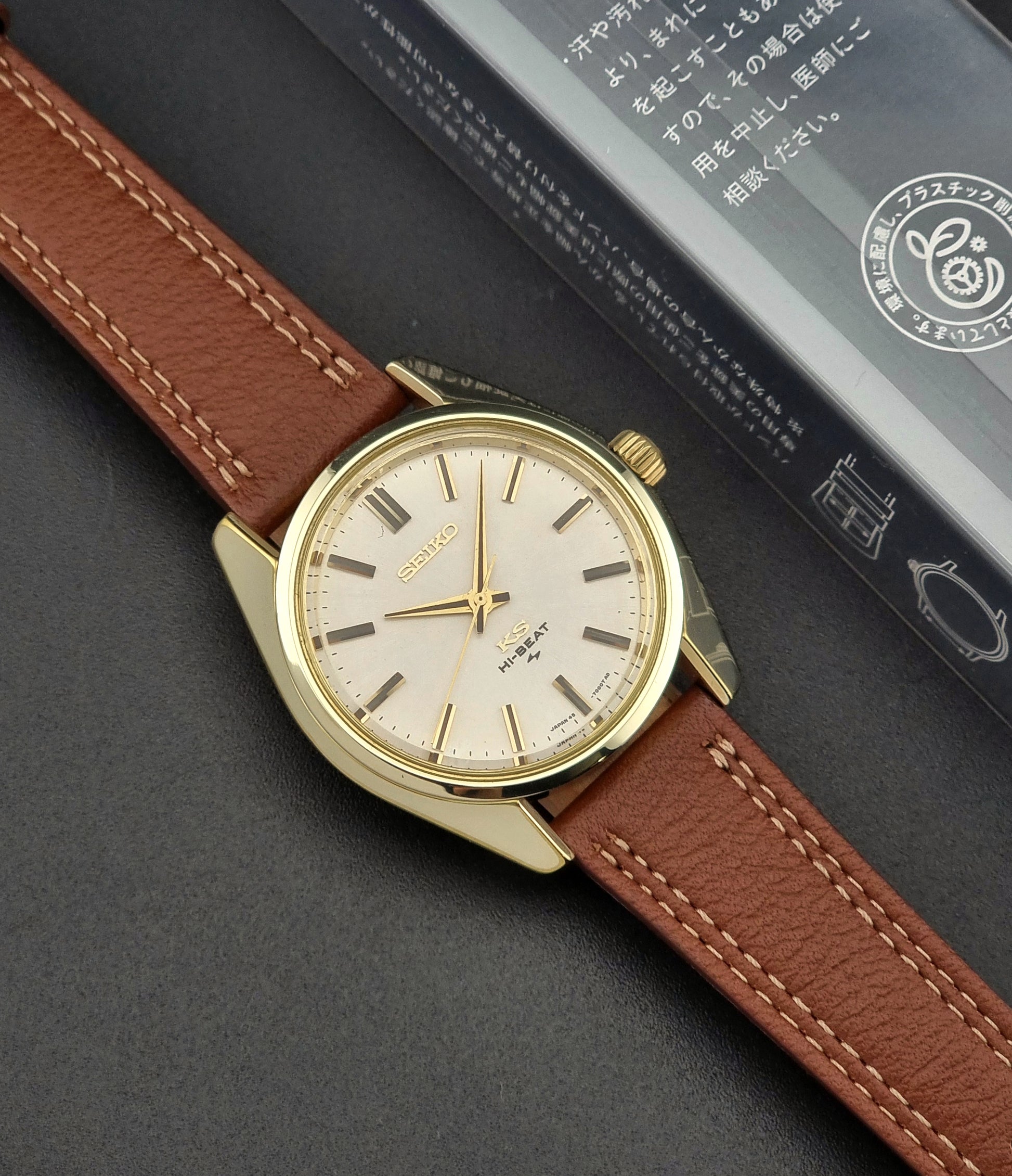 Gold Vintage King Seiko watch with brown leather strap on a dark surface