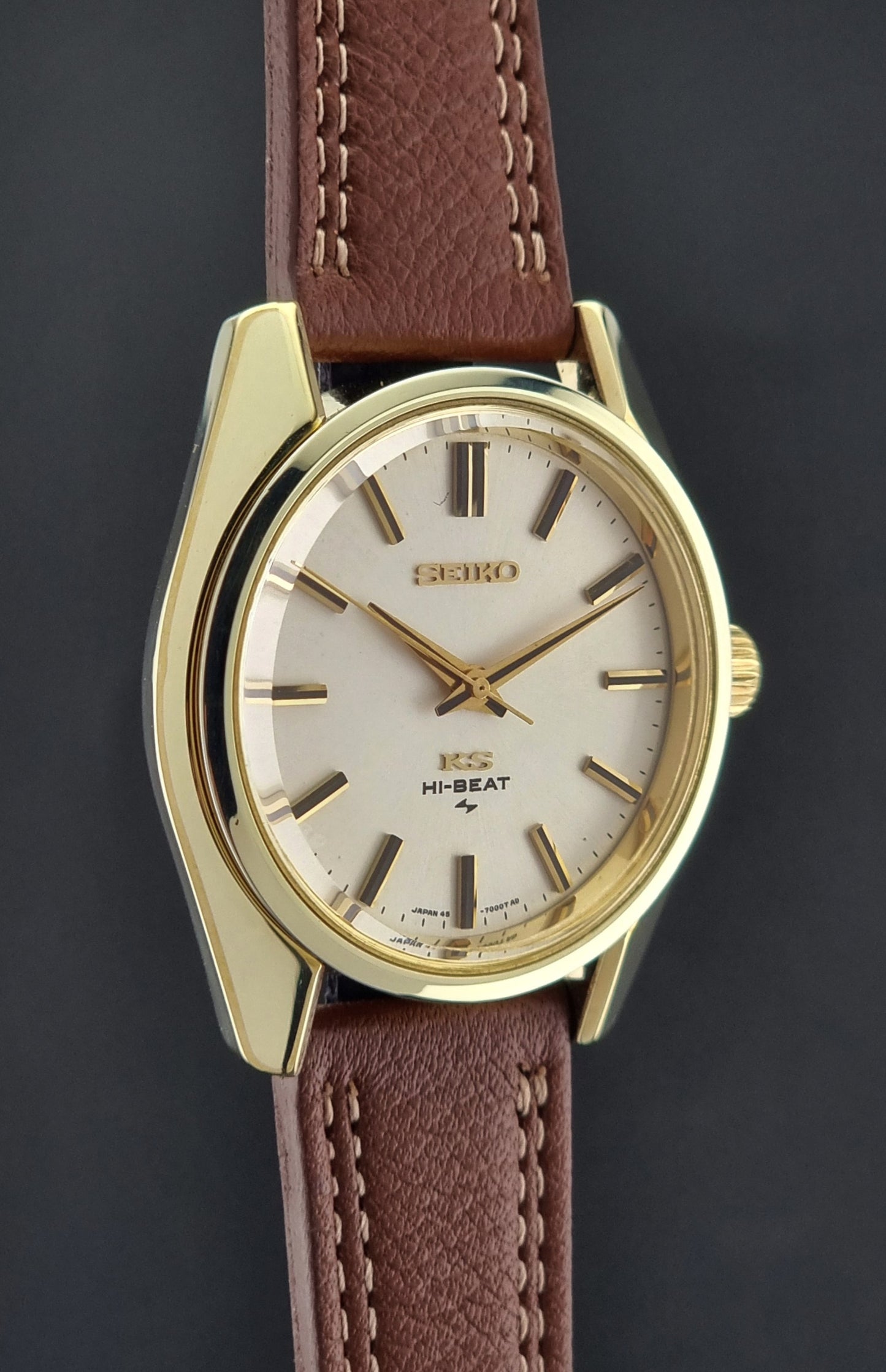 Vintage King Seiko watch with gold case and brown leather strap on a dark background
