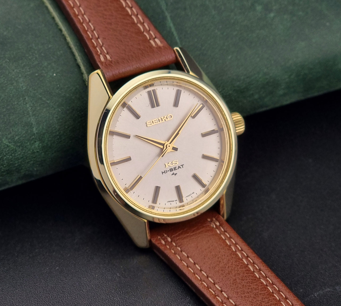 Gold Vintage King Seiko watch with brown leather strap on a dark surface