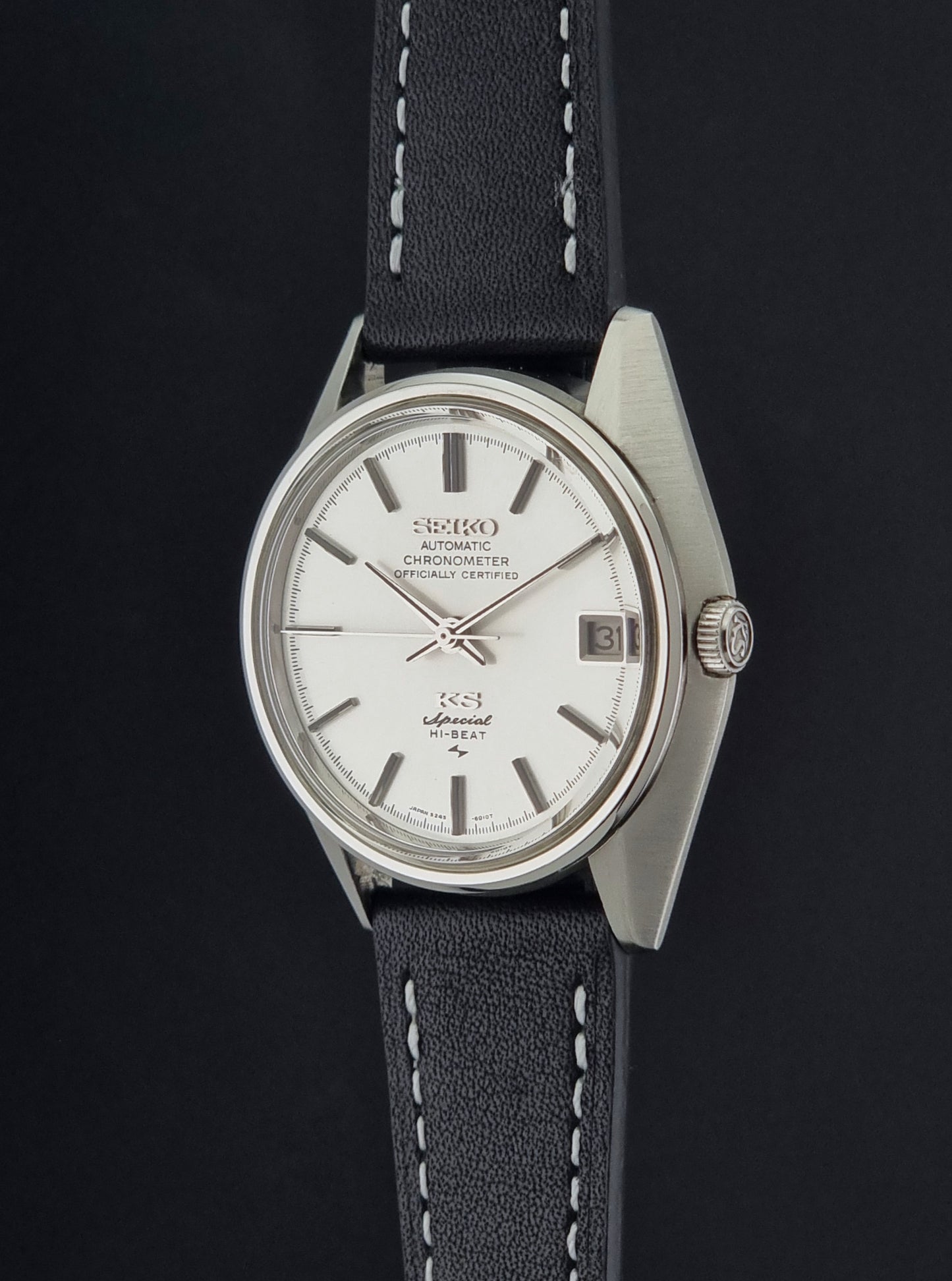 A Vintage King Seiko Special 5245-6010 Watch, white dial, and black leather strap with white stitching, photographed crown side profile against a dark background.