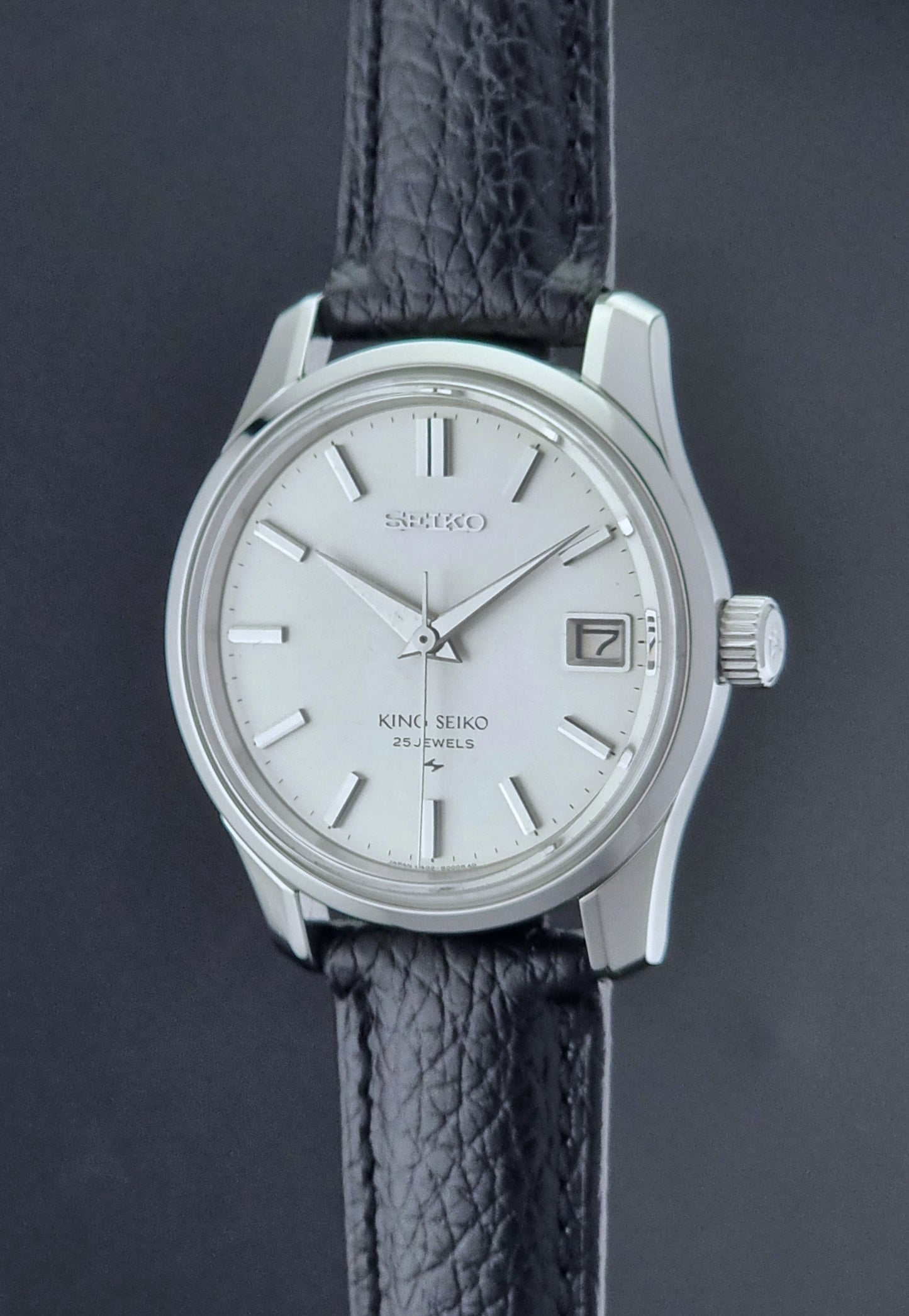 Vintage King Seiko Wristwatch with black leather strap on a dark background crown profile