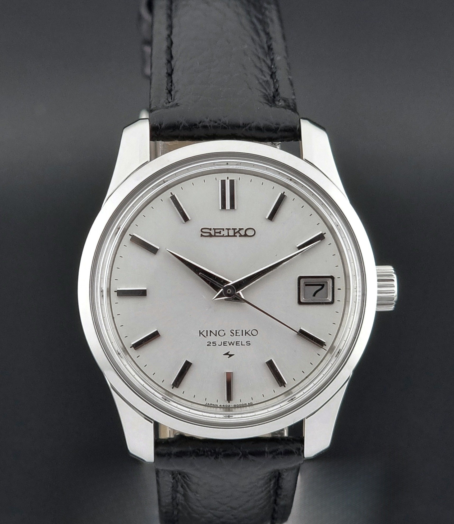 Vintage King Seiko Wristwatch with black leather strap on a dark background dial view