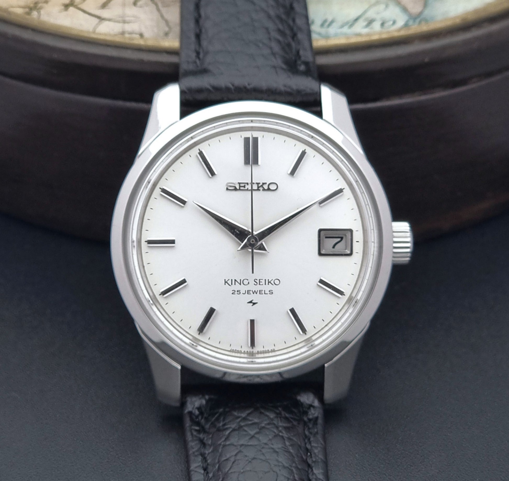 Vintage King Seiko Wristwatch with black leather strap on an old map background close up dial view