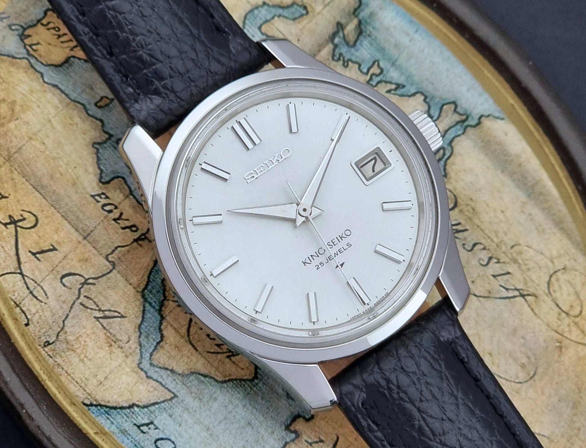 Vintage King Seiko Wristwatch with black leather strap on an old map background close dial view