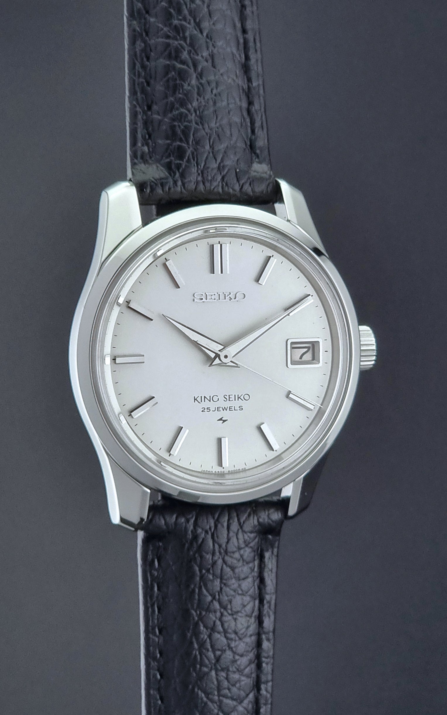 Vintage King Seiko Wristwatch with black leather strap on a dark background side profile