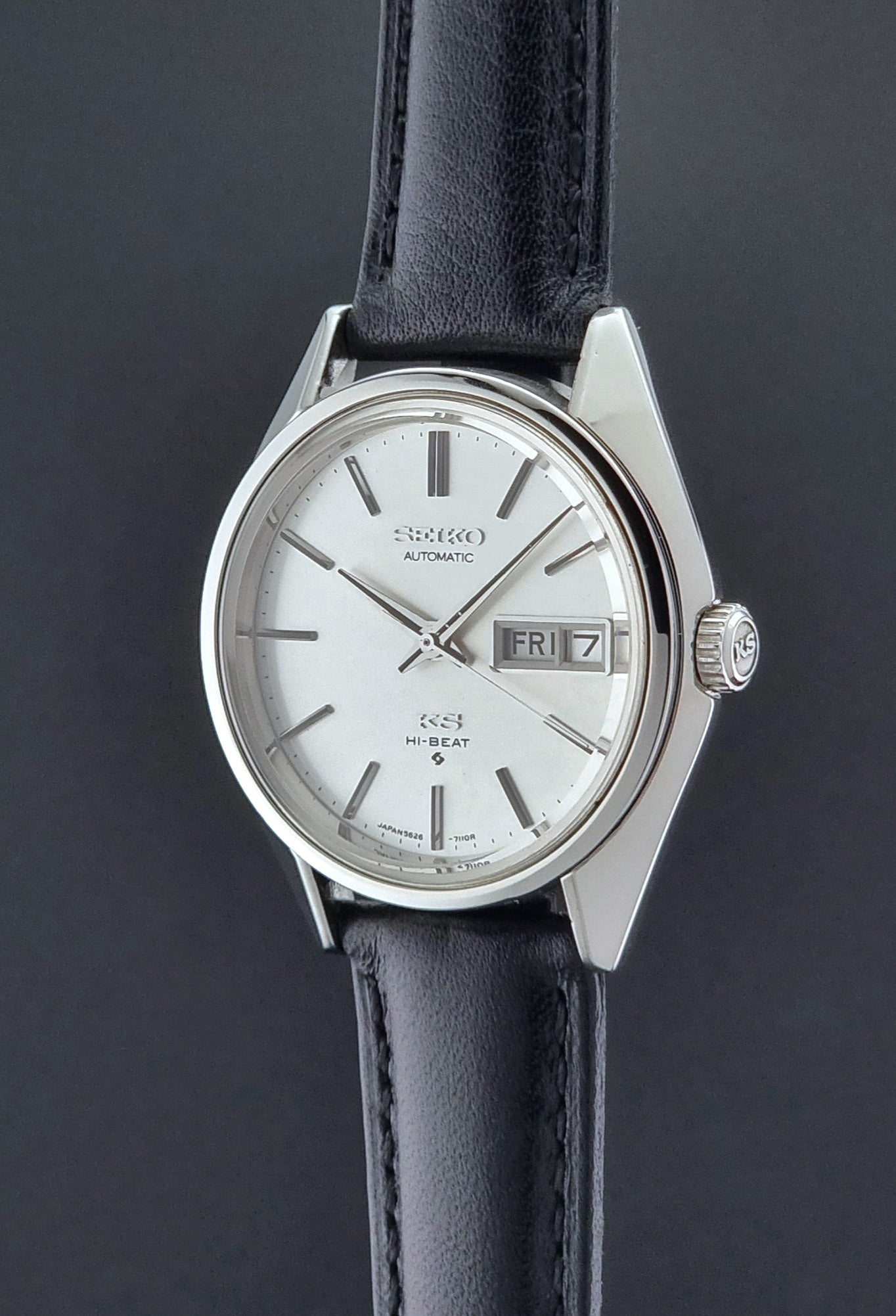 Vintage King Seiko Wristwatch with black leather strap and silver case on a black background crown profile