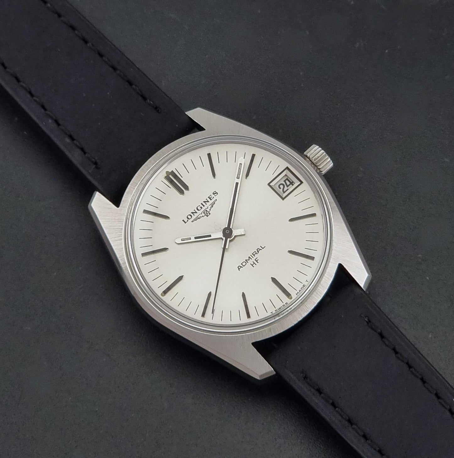 A Vintage Longines Admiral HF 2302 Wristwatch and black leather strap, photographed diagonally on a dark textured background.