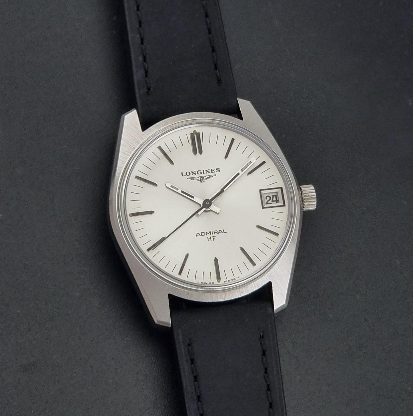 A Vintage Longines Admiral HF 2302 Wristwatch and black leather strap, photographed on a dark textured background.