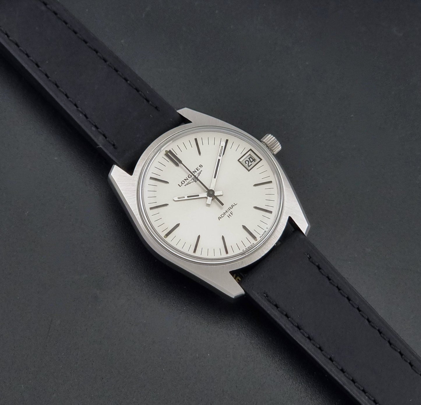 A Vintage Longines Admiral HF 2302 Wristwatch and black leather strap, photographed diagonally on a dark textured background.