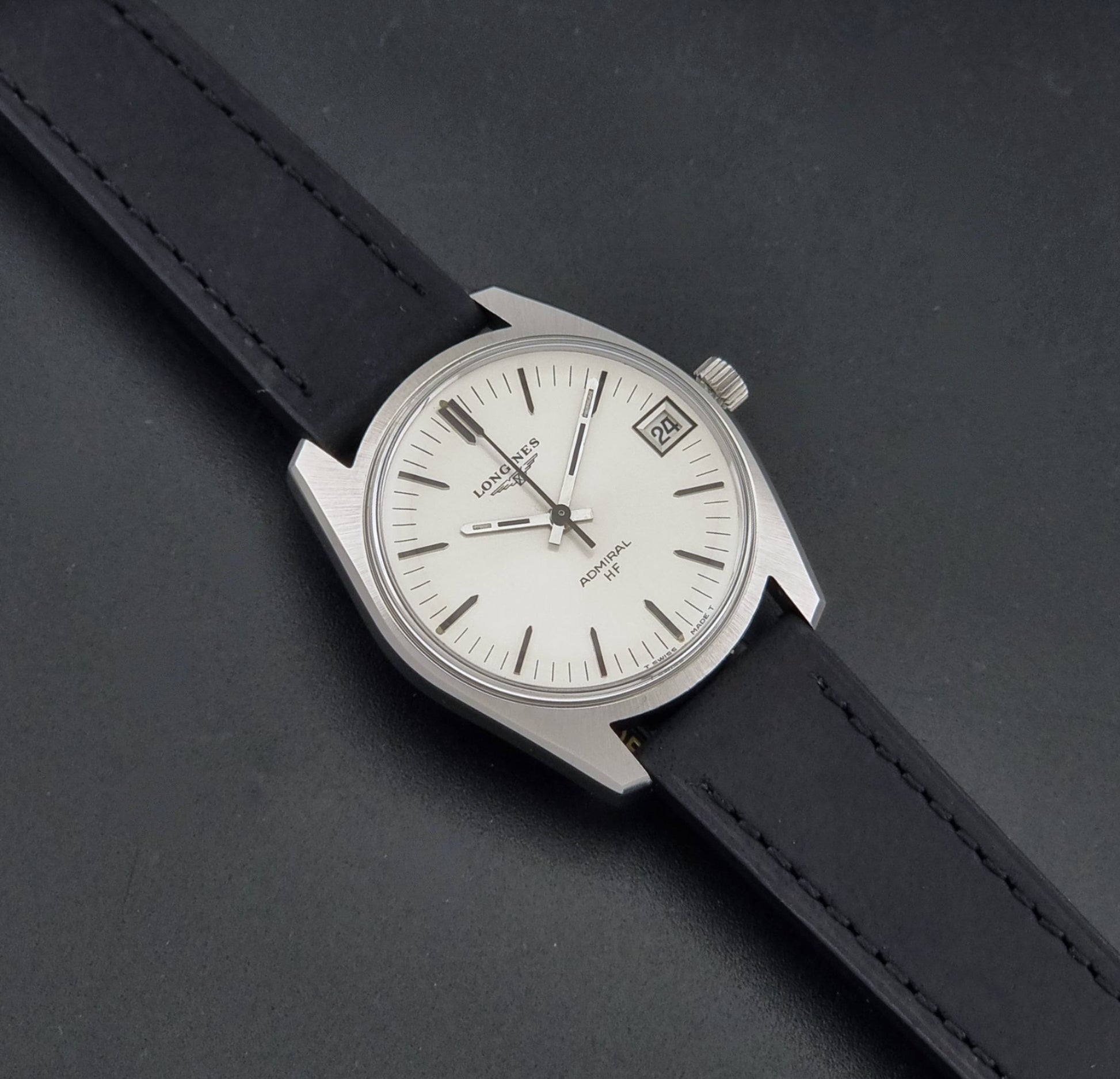 A Vintage Longines Admiral HF 2302 Wristwatch and black leather strap, photographed diagonally on a dark textured background.