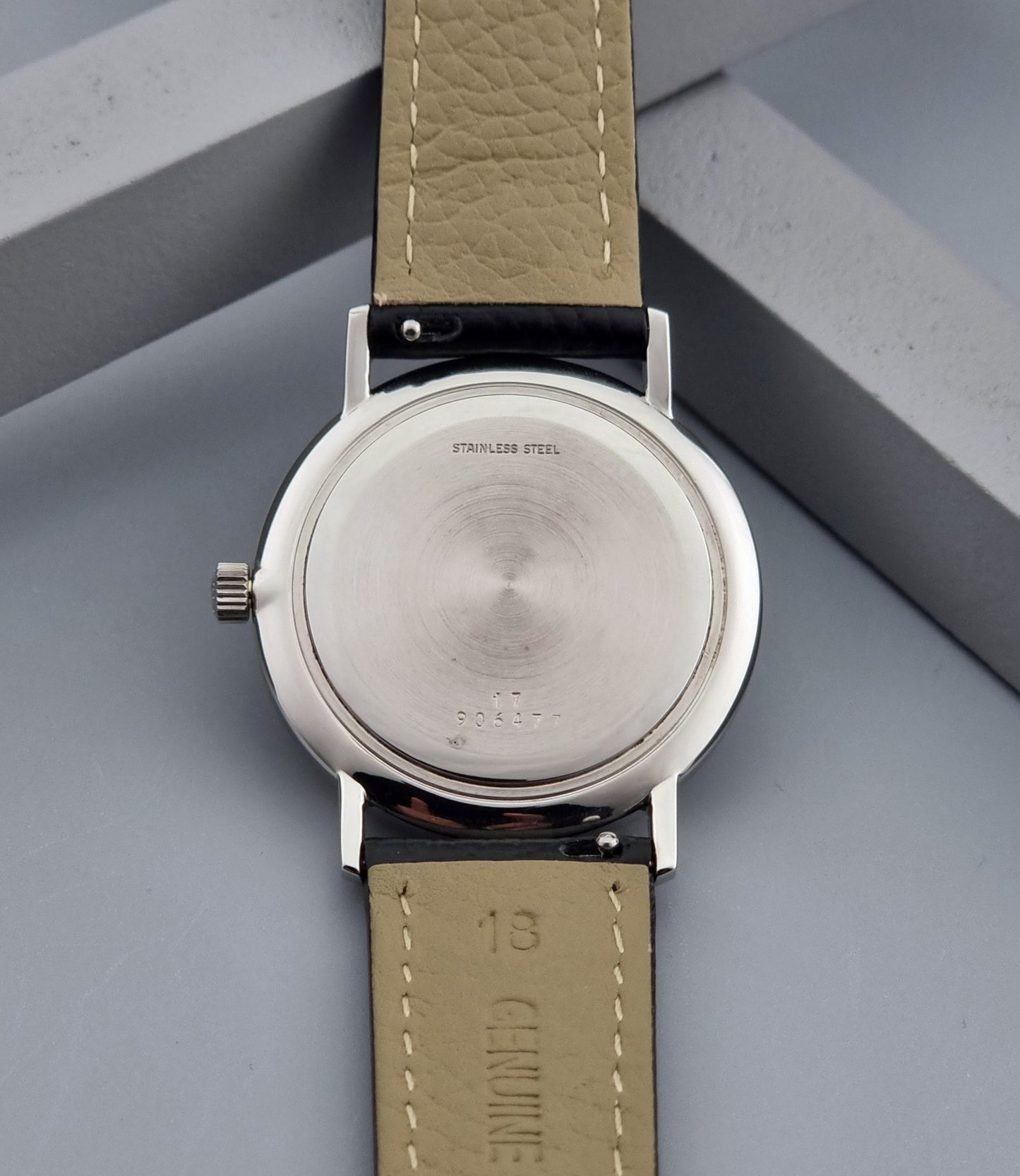 Vintage Longines Wristwatch with black leather strap and silver case on a gray background case back view