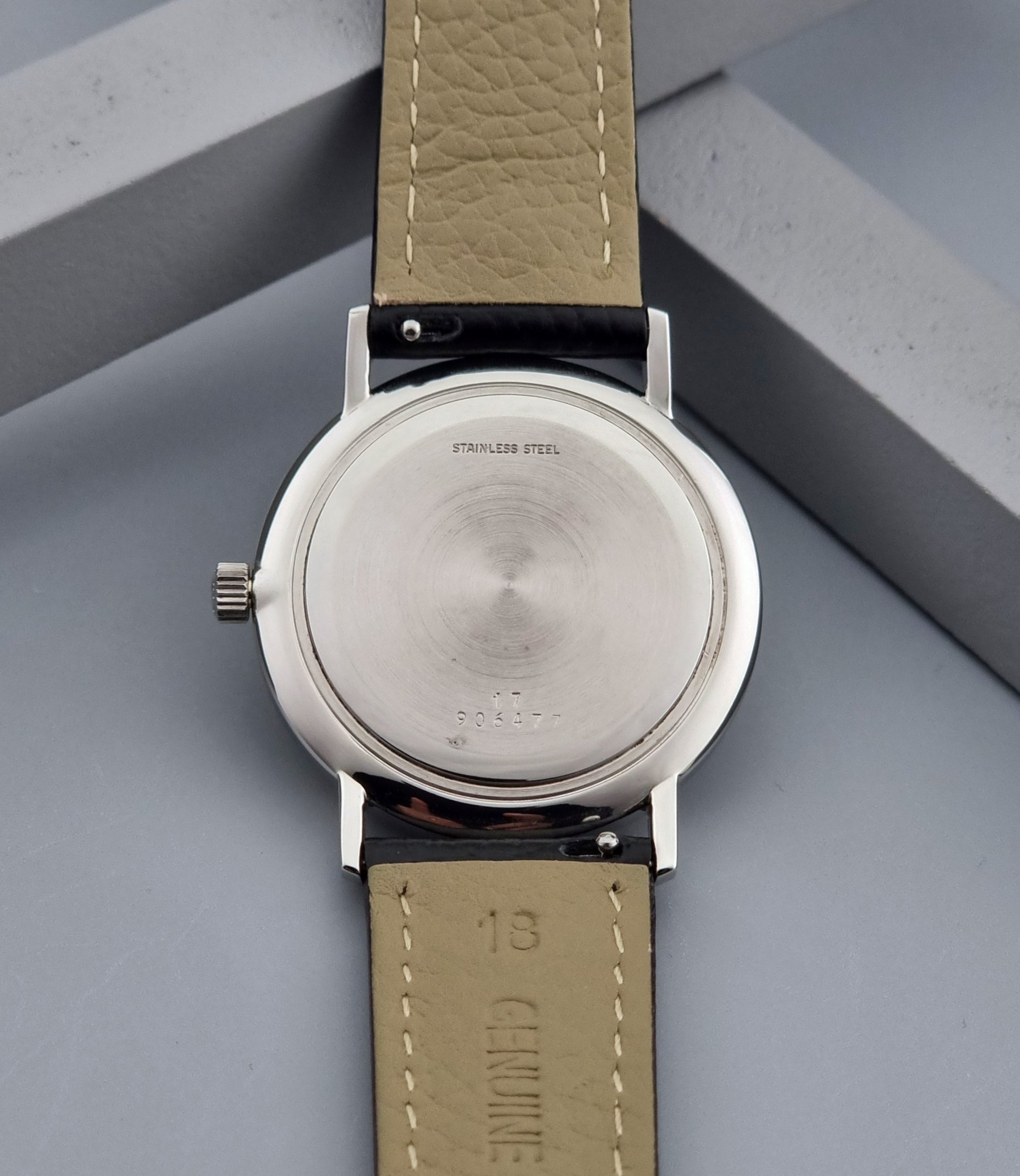 Vintage Longines Wristwatch with black leather strap and silver case on a gray background case back view